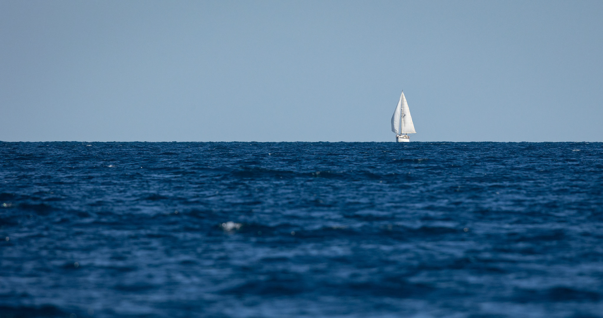 A sailing boat on the horizon in the waters of Platypus Bay off the coast of Fraser Island, Australia