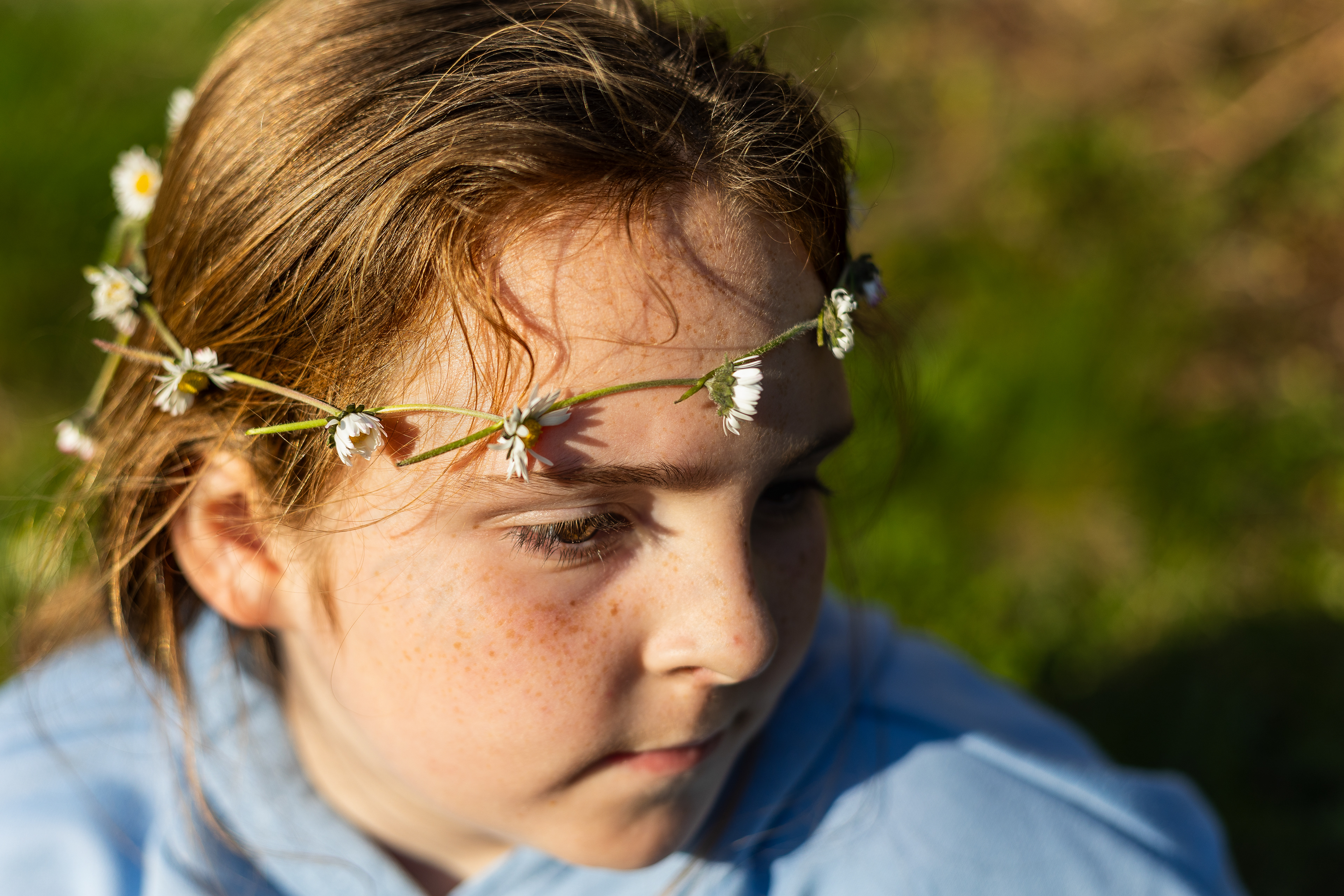 Leanne Edge - Daisy Chain Portrait. An unposed, naturalistic documentary portrait from Project Seven, capturing a moment of stillness and introspection. This South Wales photography study features strong textures and focuses on the sensory experience of a child in nature, exploring themes of memory and youth.