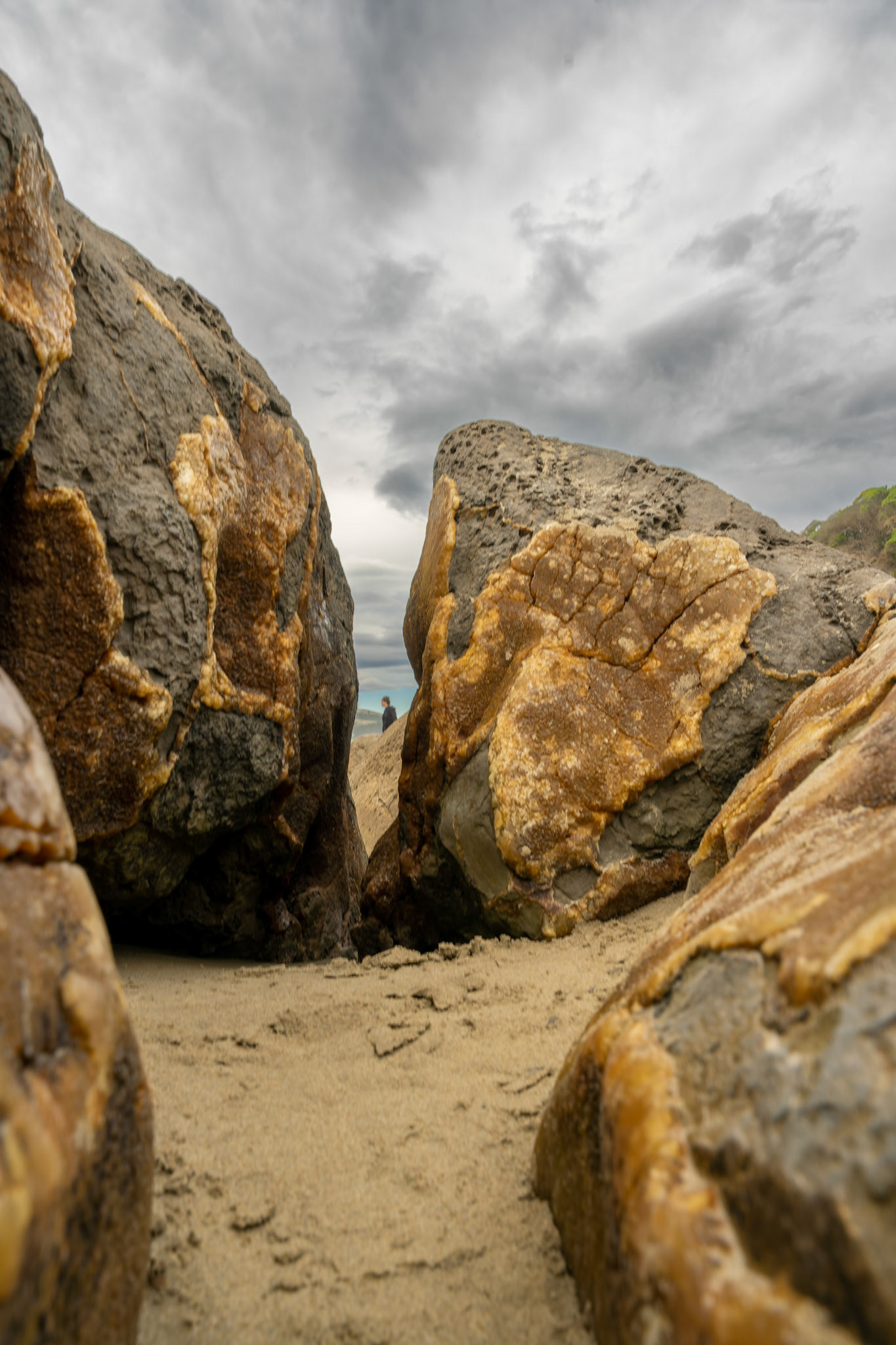 Looking at someone through the crack in a colourful boulder in Moeraki New Zealand