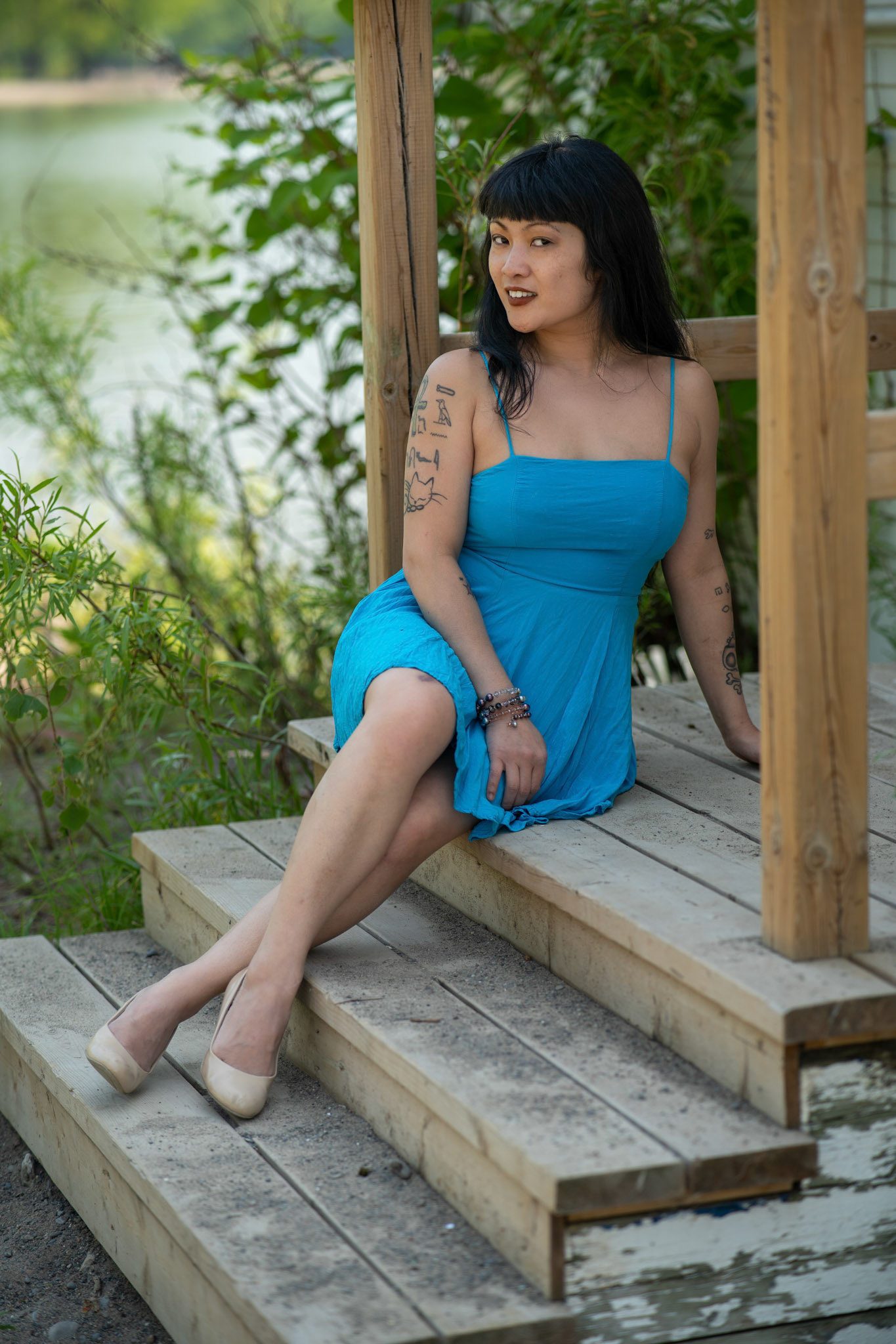 Carmen Chan in a blue summer dress sitting on the steps of a beach house
