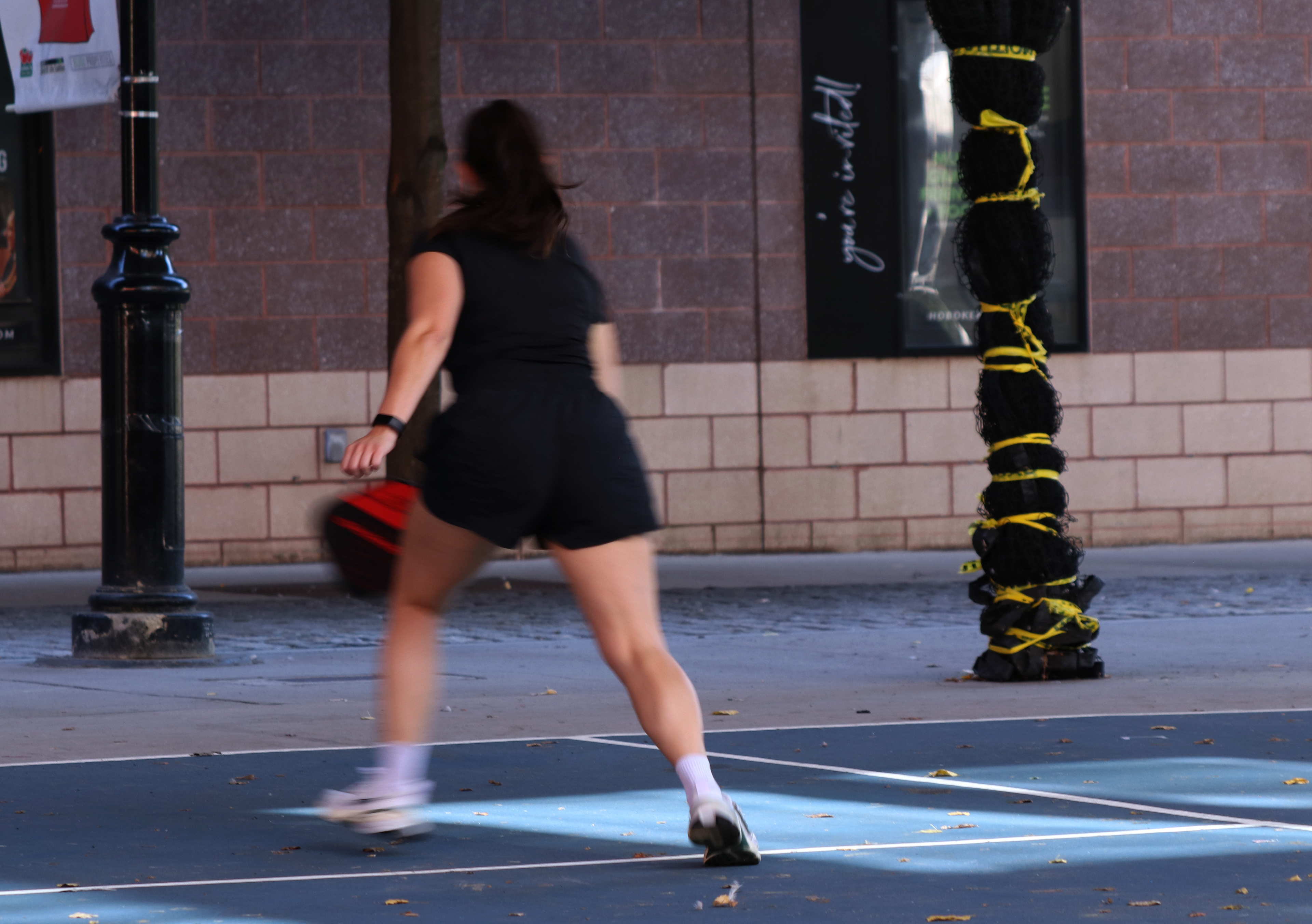 HOBOKEN, NJ, 10-05-2024 FAST MOVEMENT WITH MOTION BLUR: A woman plays tennis in 14th street in Hoboken, New Jersey, on October 5. This photograph shows a a fast movement with motion blur as she runs to get the ball.