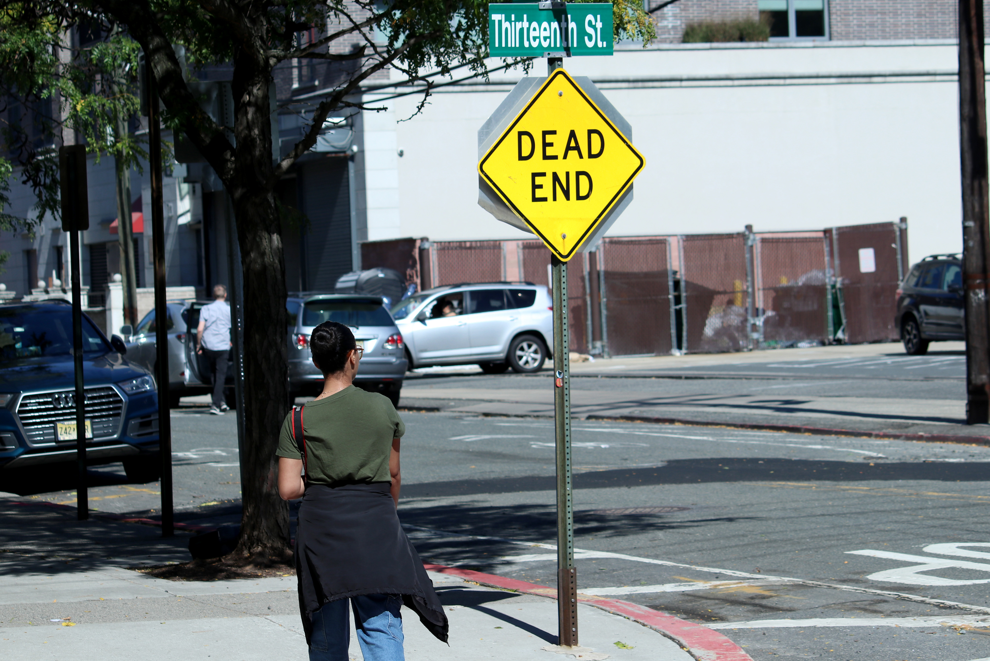 HOBOKEN, NJ, 10-05-2024 SIGN SHAPE WITH A PERSON IN FRAME: A walks by the "DEAD END" sign in Hoboken, New Jersey, on October 5. This composition creates a contrast between the sign's message and people, indicating that the street ends right in the corner.
