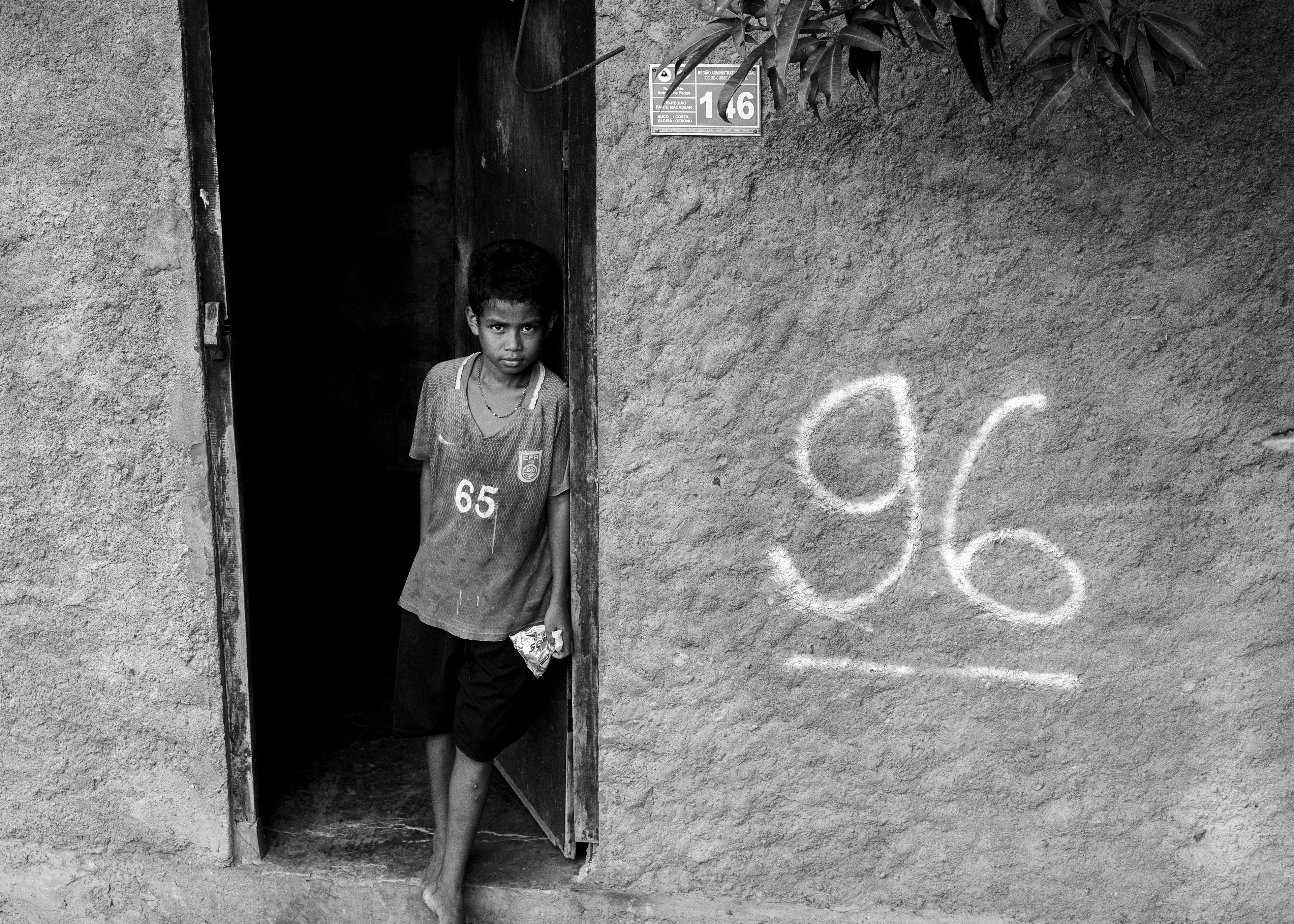 A boy stands at the doorstep of his home, which has been marked by the government for demolition due to development.
