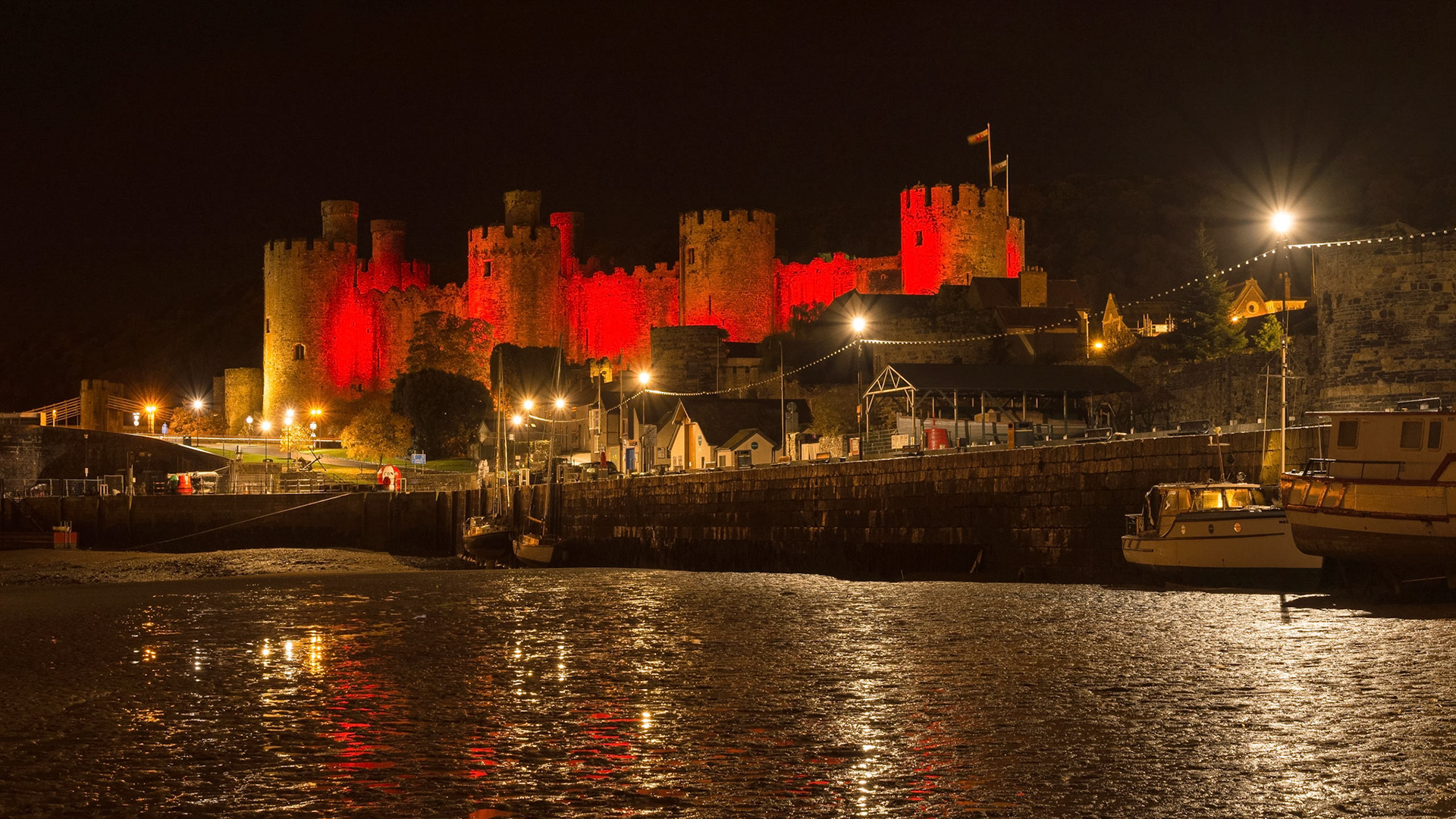 Conwy Castle in Snowdonia, North Wales, lit up red on a winter evening.