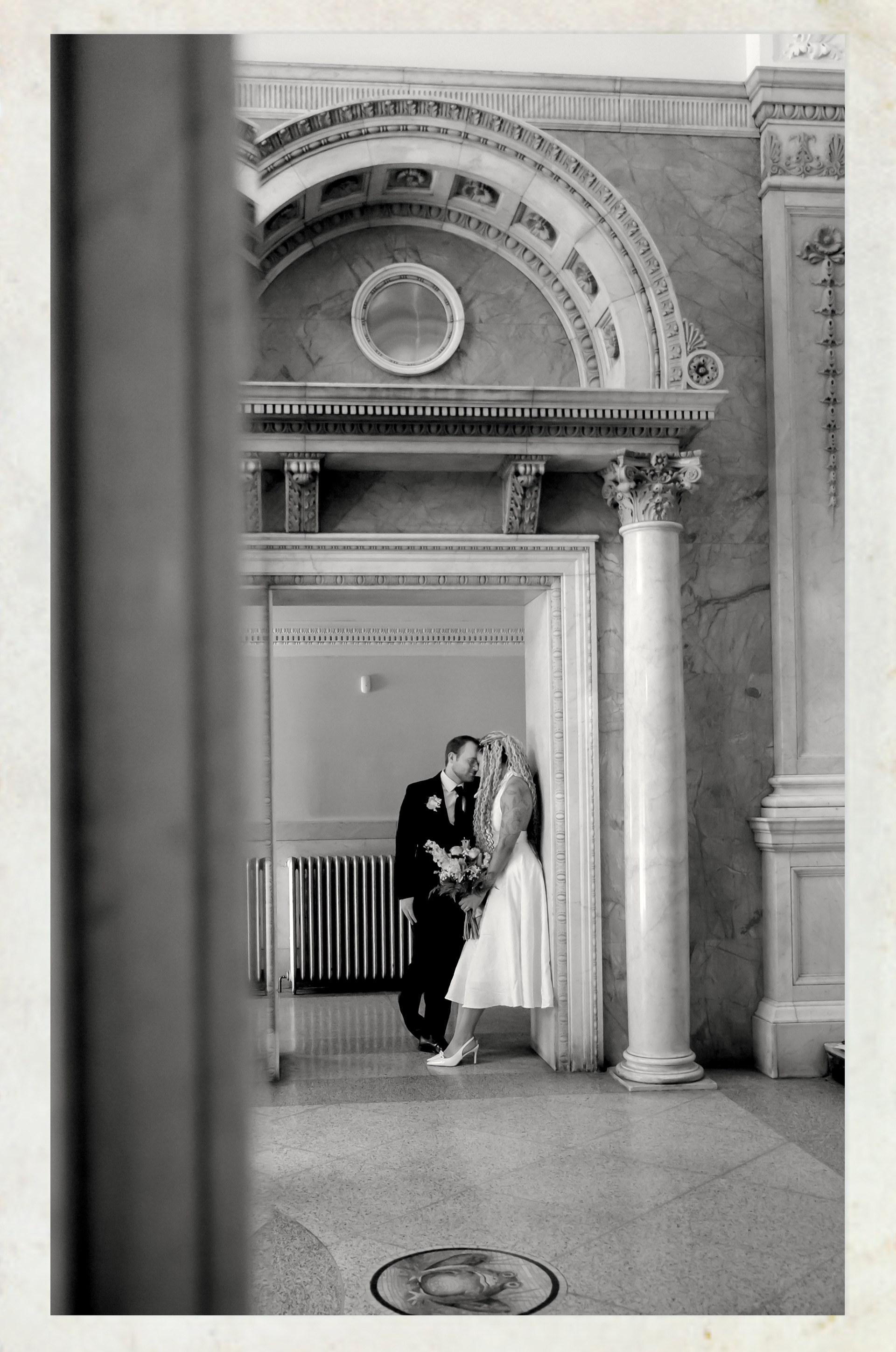 Black and white image of a 20-30 year old couple in an old courthouse archway. Toledo, Ohio Elopement and Courthouse Wedding Photographer.