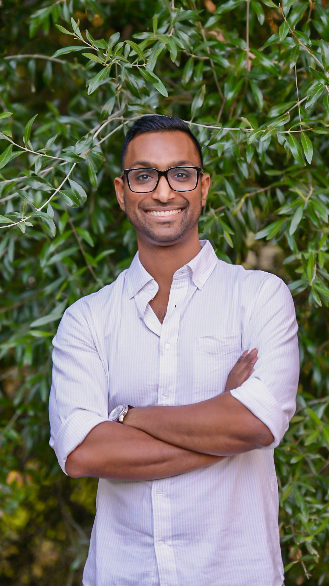 A professional and clear portrait of photographer against a green bushy background