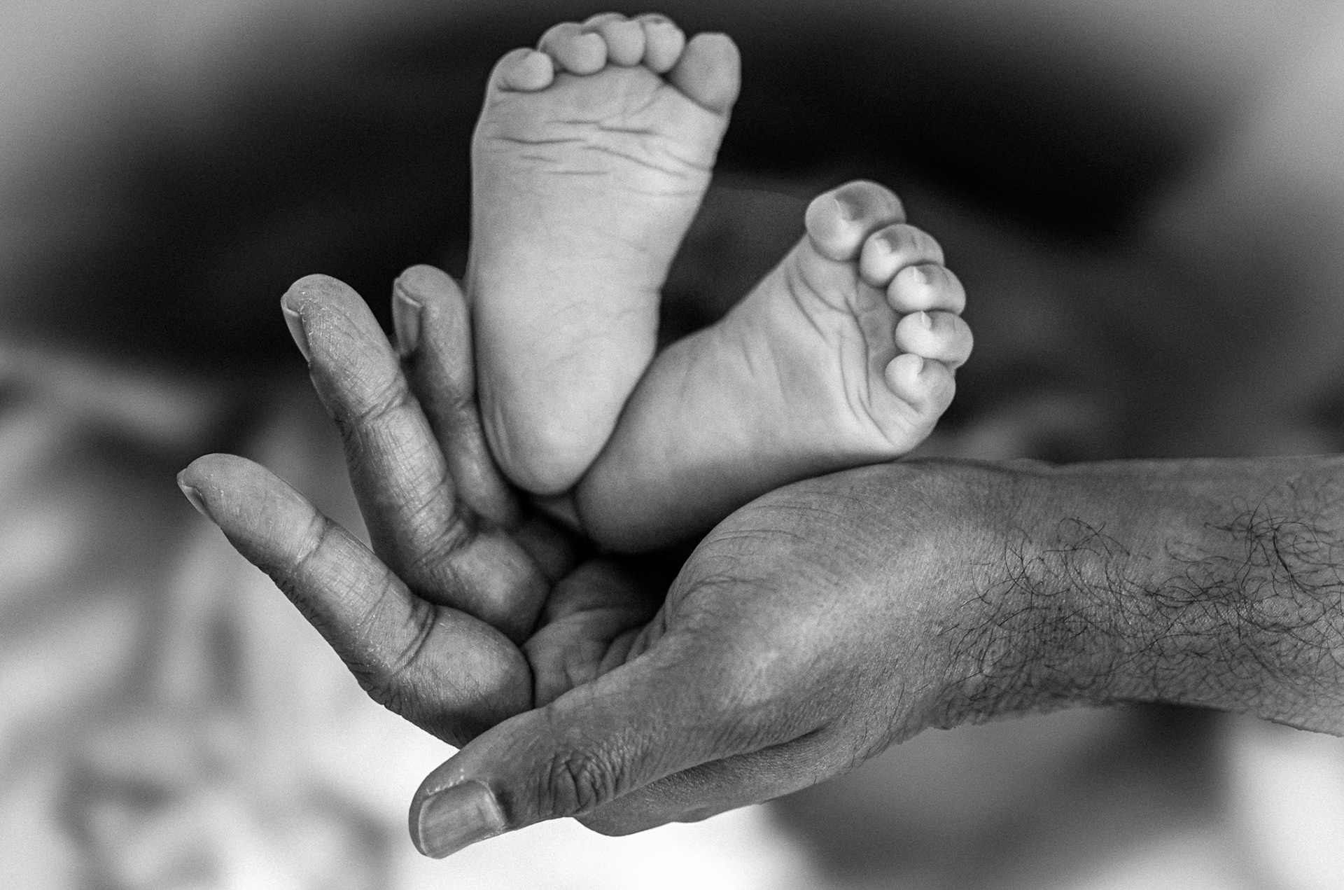 Black and white shot of a father's hand holding his newborn feet