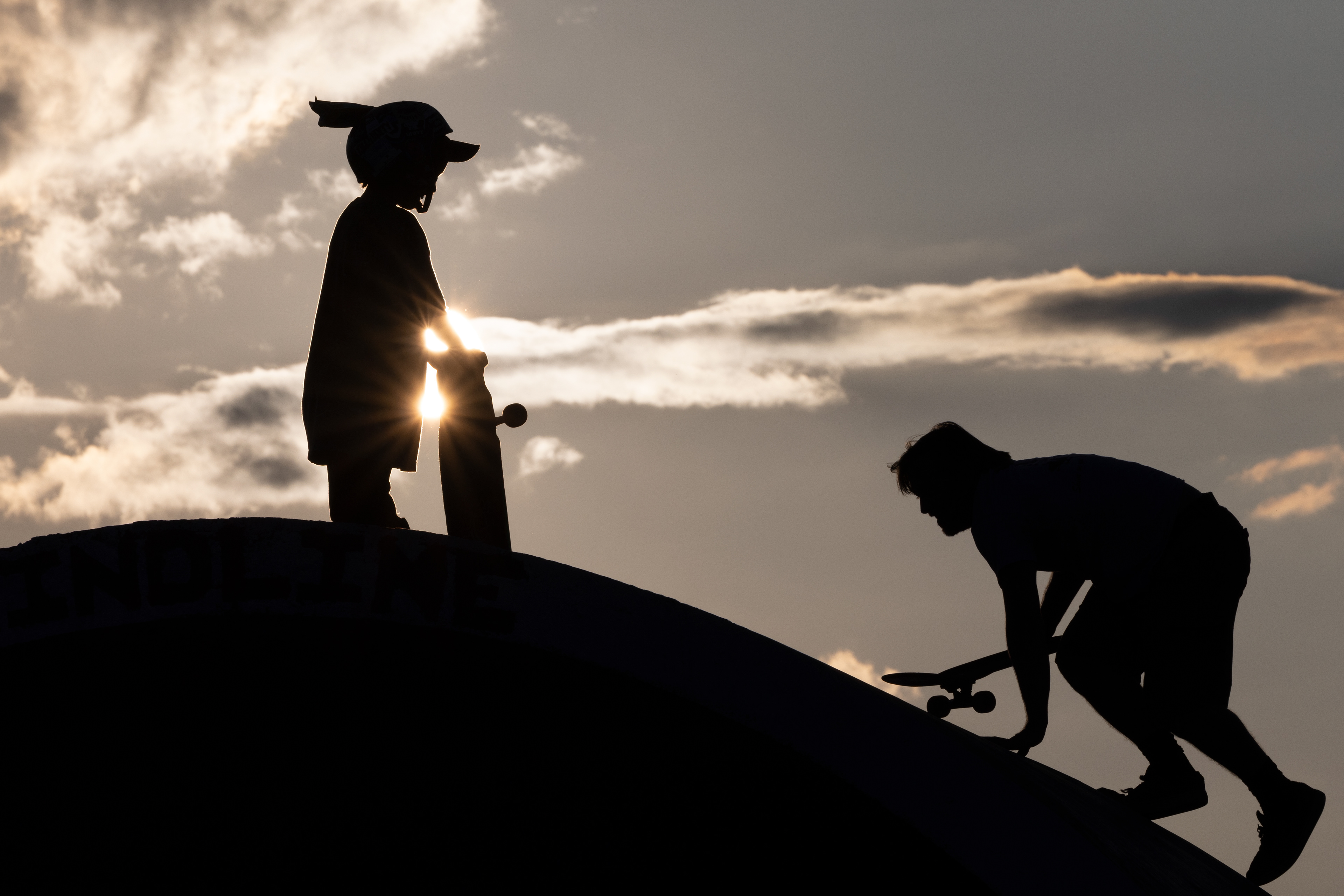 A silhouette of Ezra Gallagher (left) and Joey Bolin stand on top of the Vader dome at the Athens Skatepark in Athens, Ohio, Sept. 29, 2023. Even though Ezra is more than a decade younger, he pushes Joey to become a better skater and to try new tricks. The community does not discriminate against age, race, or gender. Everyone is welcome and everyone gets along.