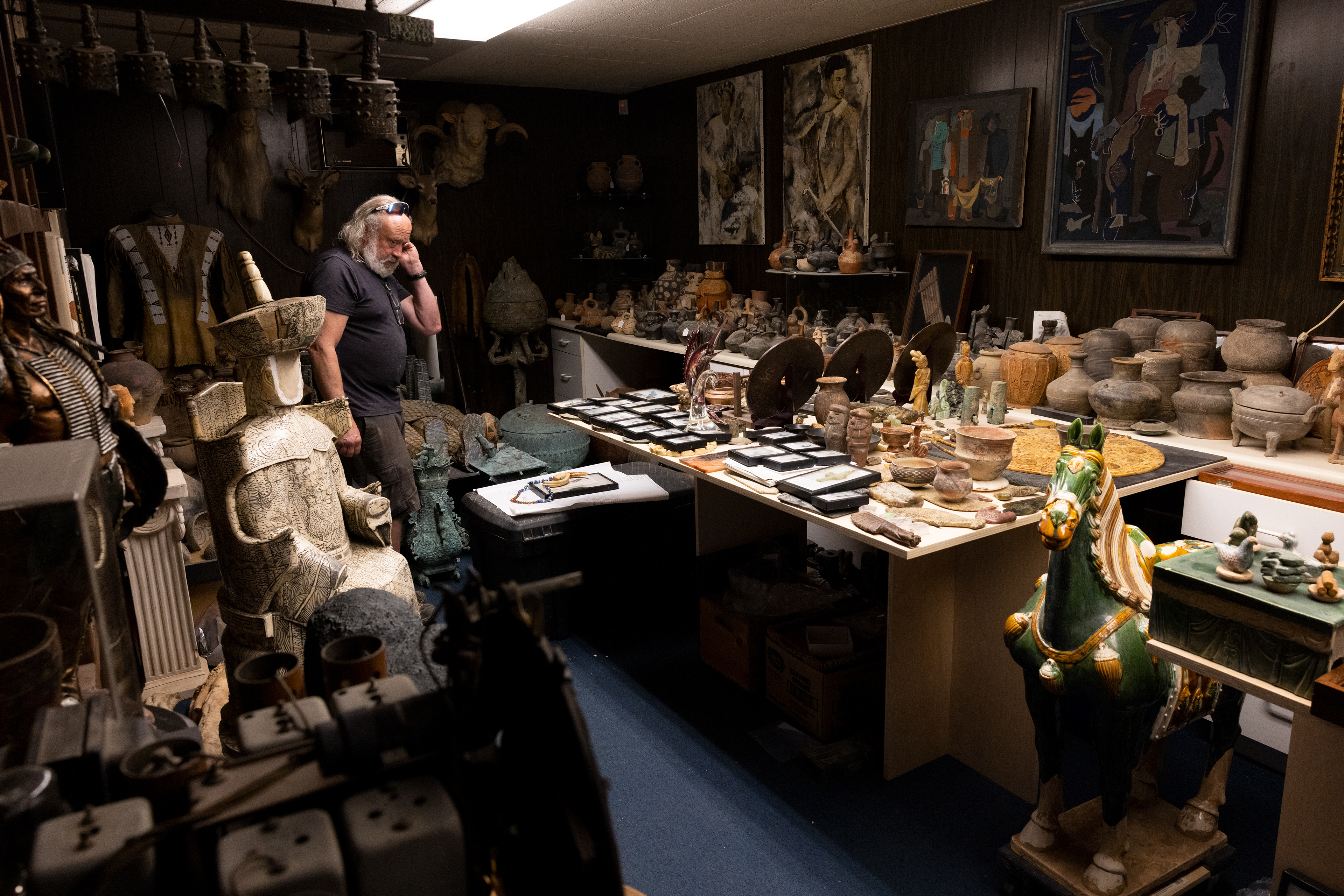 Chuck Harnack stands in his workshop’s vault in Downtown Columbus, Ohio, Sept. 5, 2023. The secured room is near his office and holds thousands of ancient artifacts. Pad locks, sirens, and safes keep this room and the stuff in it safe. Some relics from his collection date back to 3000 B.C. and a few are older than that. Chuck has fragments of historical events from all over the world. Dinosaur skeletons, a jade emperor burial suit, hundreds of Chimú whistling vessels, and other historical items are laying around this room. He has been collecting since he was little and has never stopped. The vault is too small for his collection, and he now keeps some of it in his house. The furniture business helps pay for his hobby or what he calls, “bad habits.”