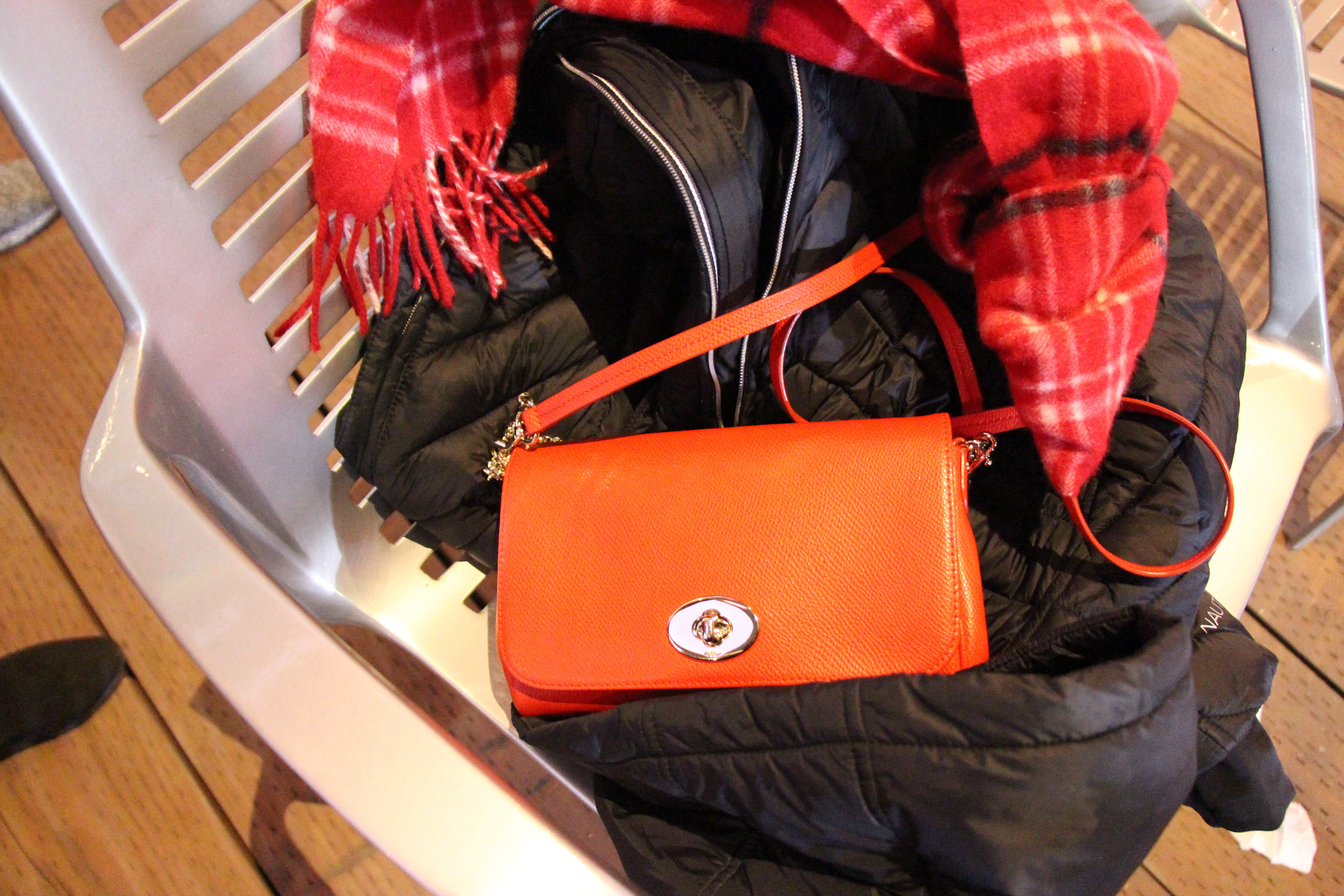 Composition: The red-orange bag is placed in the center while the jacket and scarf is laying around the bag.