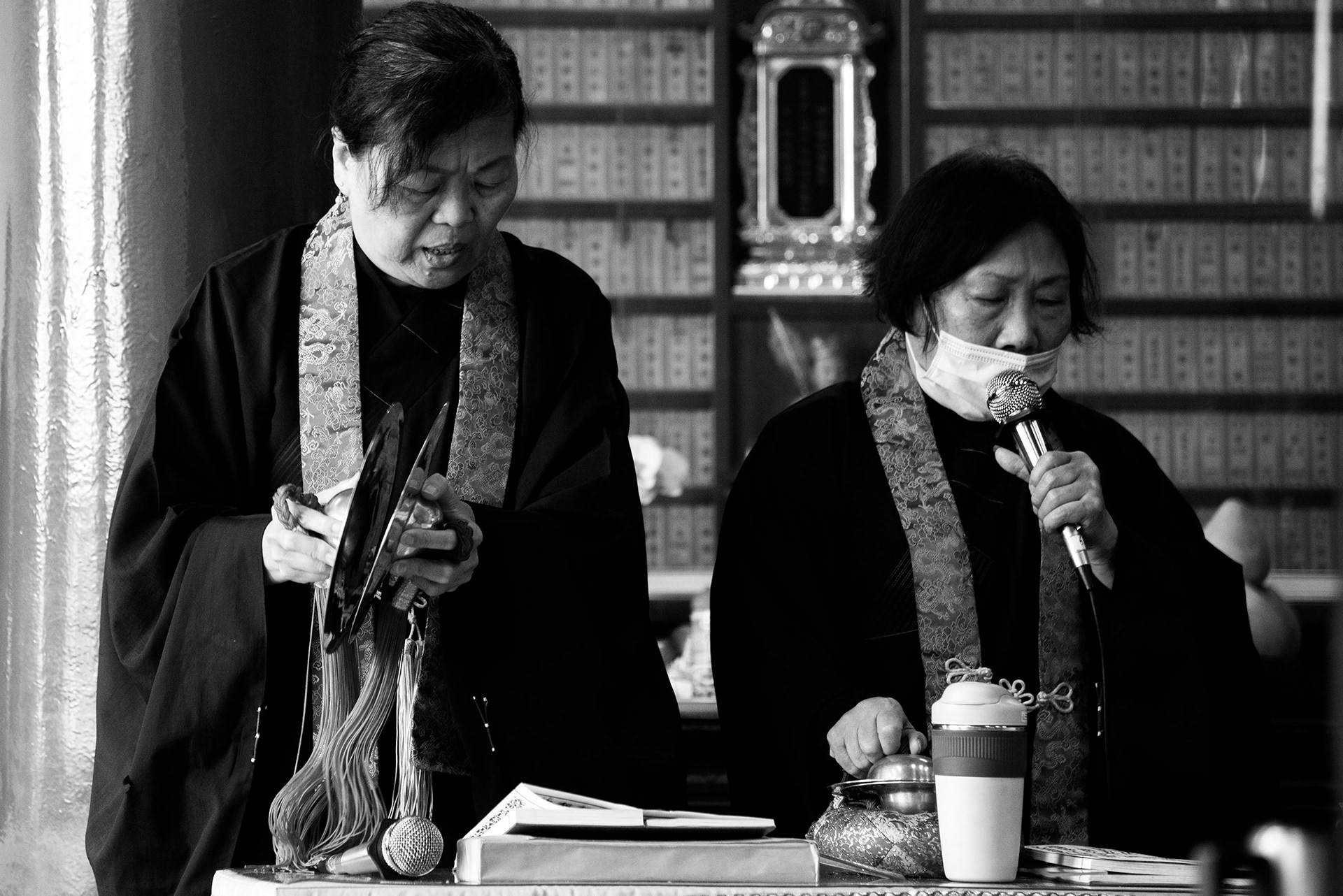 two women pray and ring the tingsha during the ceremony