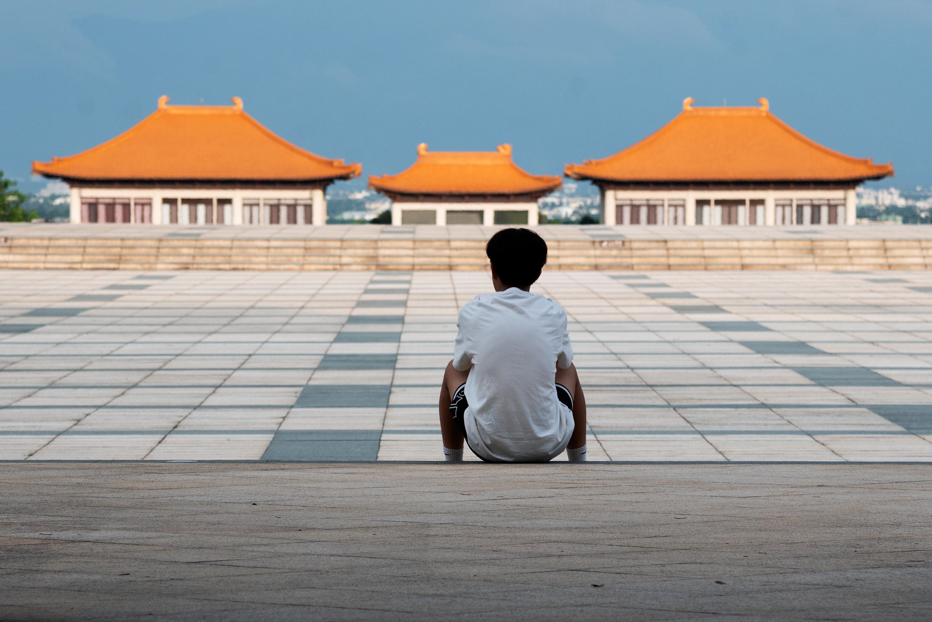 outside a temple in Kaohsiung, a boy sits in silence, contemplating the sweeping view before him