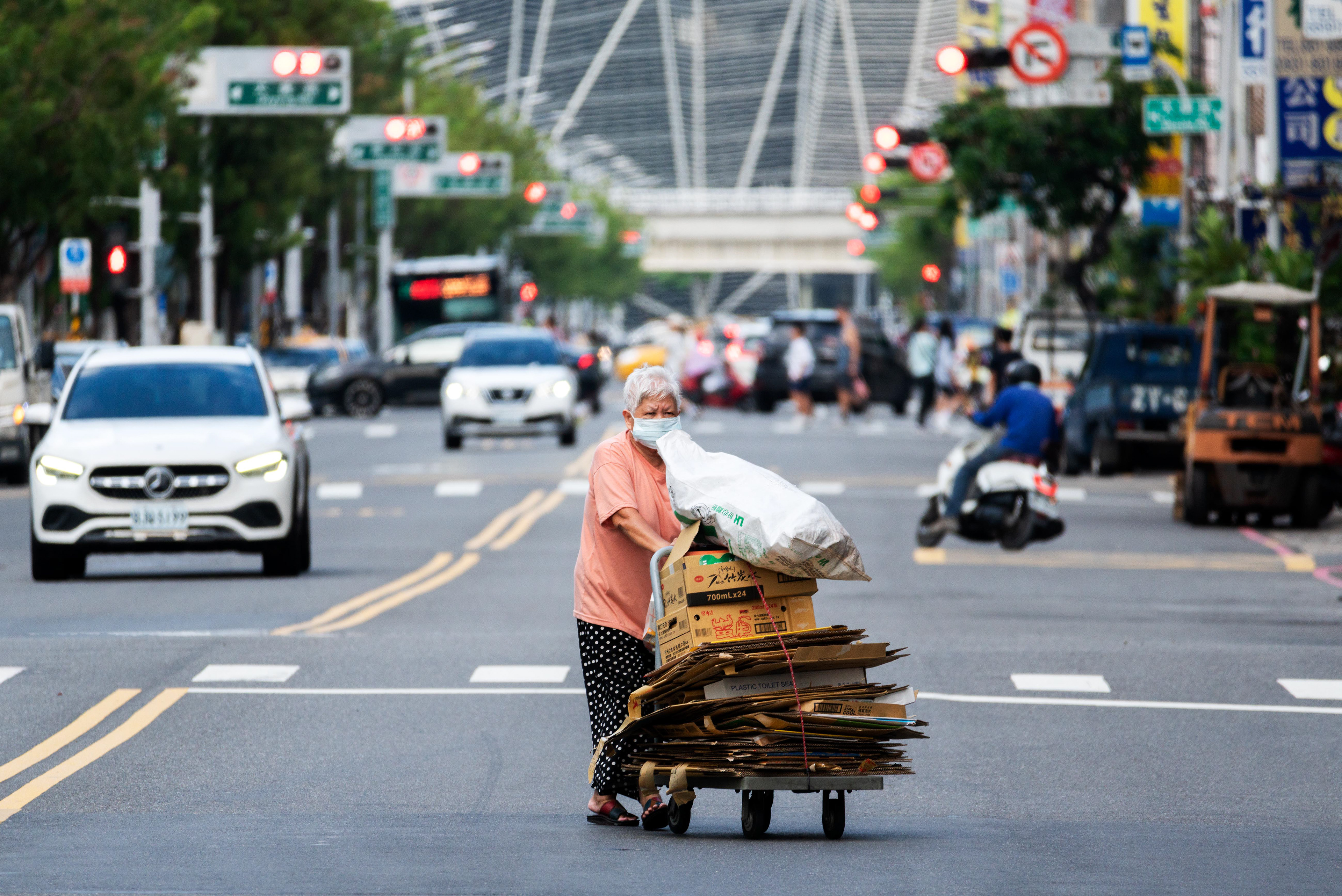 an elderly woman transports used cardboard to sell