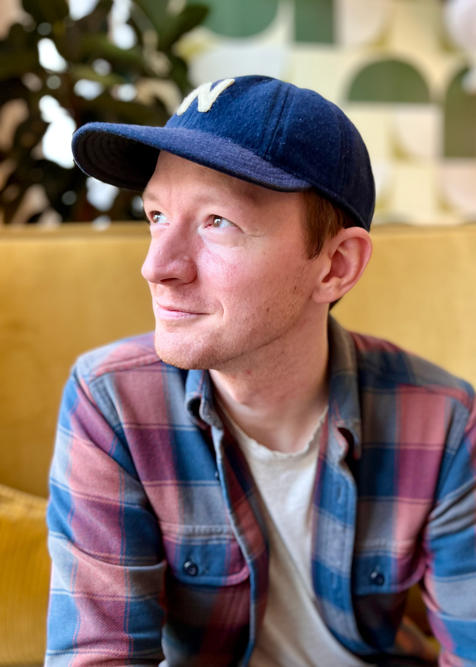 Niles Kealy, while wearing a baseball cap with the letter "N", looks off to the left with a smile on his face