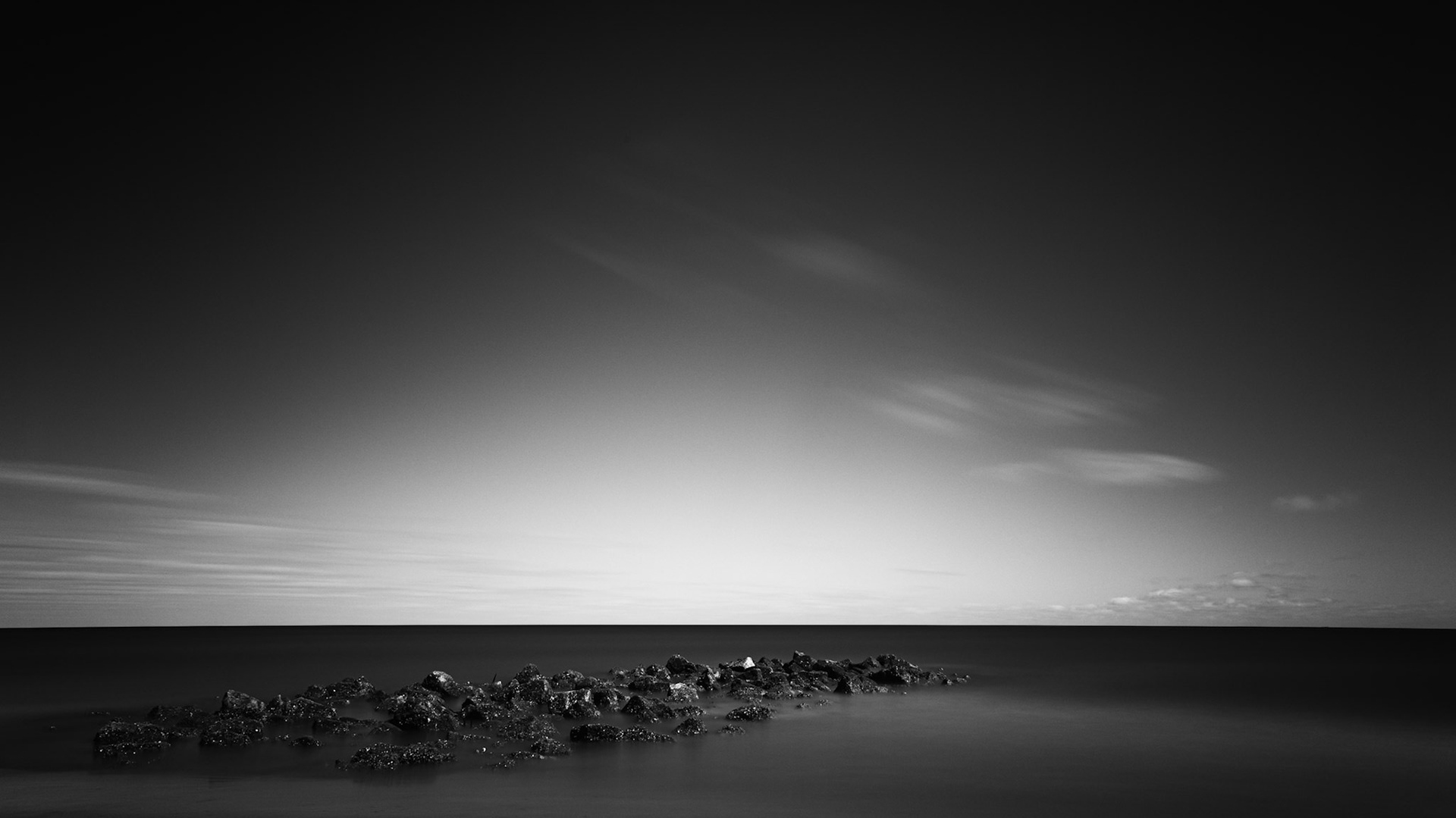 STILL HORIZON  |  Not every landscape offers an obvious focal point. Sometimes the scene appears almost empty, and it is only through patience and a different way of seeing that its character emerges.With a long exposure, the movement of water and sky dissolves into soft gradients, leaving behind a quiet conversation between light, texture, and space. The scattered rocks become an anchor in an otherwise minimalist world, inviting the viewer to slow down and appreciate the subtle beauty often overlooked in the rush to find something grand.
