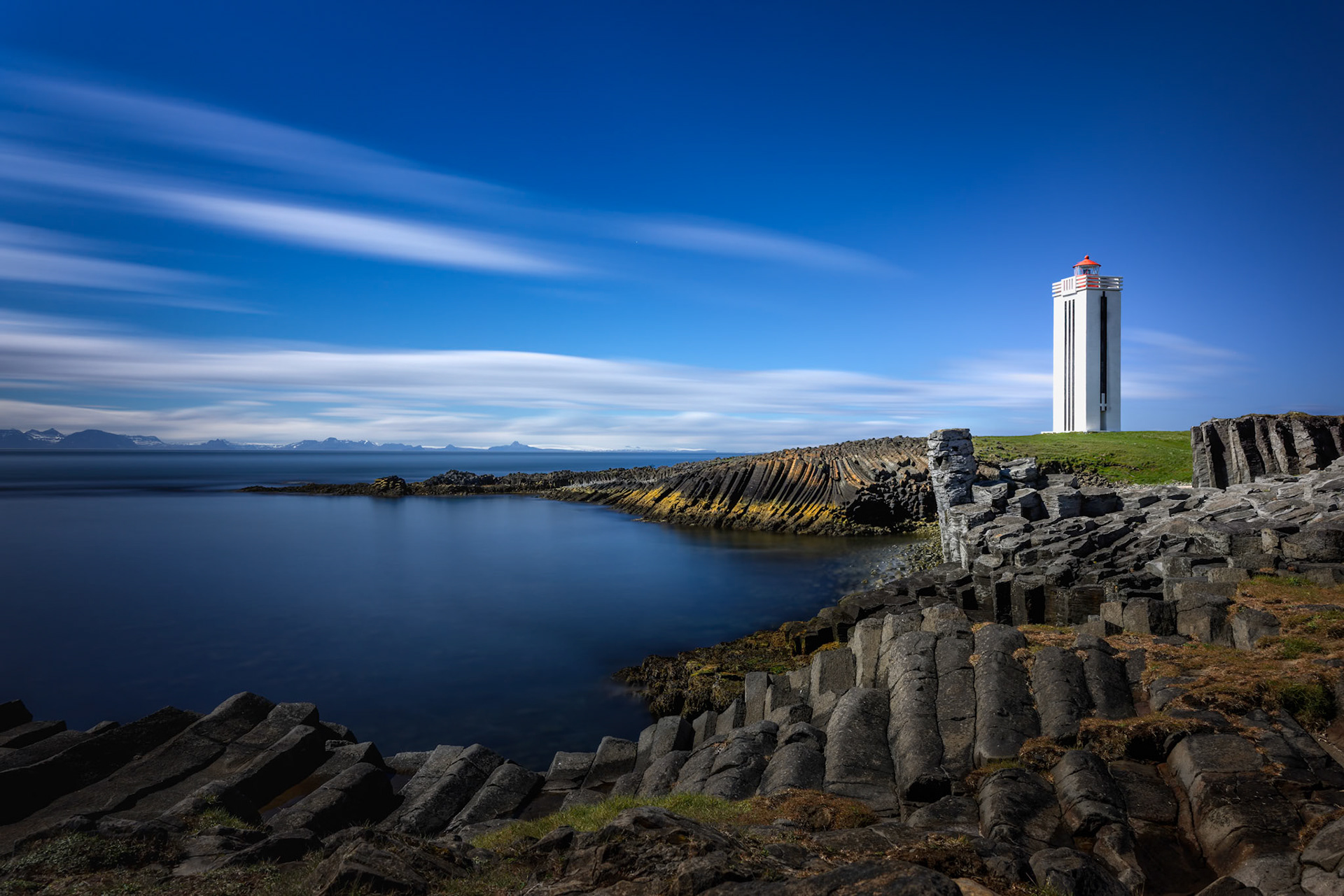 BASALT AND SILENCE  |  Along Iceland’s rugged coastline, nature and design seem to speak the same language. The towering lighthouse rises from the landscape with clean geometric simplicity, while the ancient basalt formations below mirror its vertical lines as though the earth itself sculpted the perfect foundation for it.