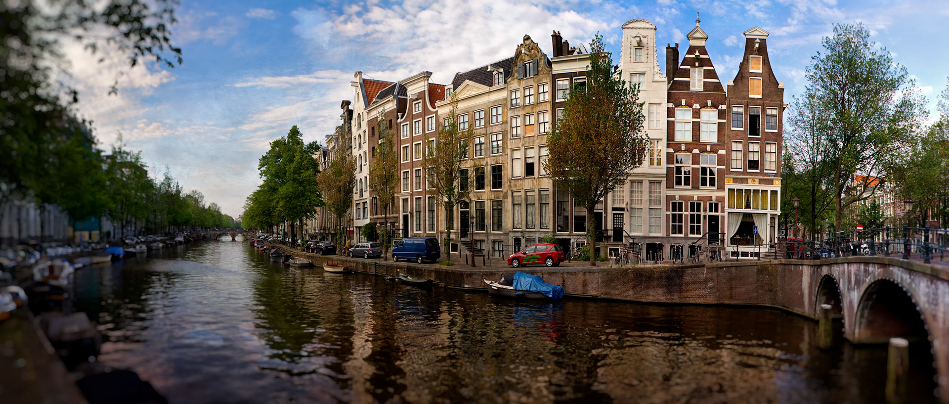 CANALS OF AMSTERDAM  |  Amsterdam has a way of slowing time. I made this photograph while wandering the city with no destination in mind, crossing bridges and following canals simply to see what was around the next corner. The quiet water, historic homes, and gentle curve of the canal felt like a scene that had changed very little over the centuries.What struck me most was how effortlessly people live alongside the water. Boats are tied up where cars might be parked elsewhere, and daily life unfolds against a backdrop of architecture that has watched generations come and go. Moments like this remind me that travel is often less about landmarks and more about discovering the character of a place.This view captures the Amsterdam I remember: unhurried, welcoming, and perfectly content to reveal itself one canal at a time.