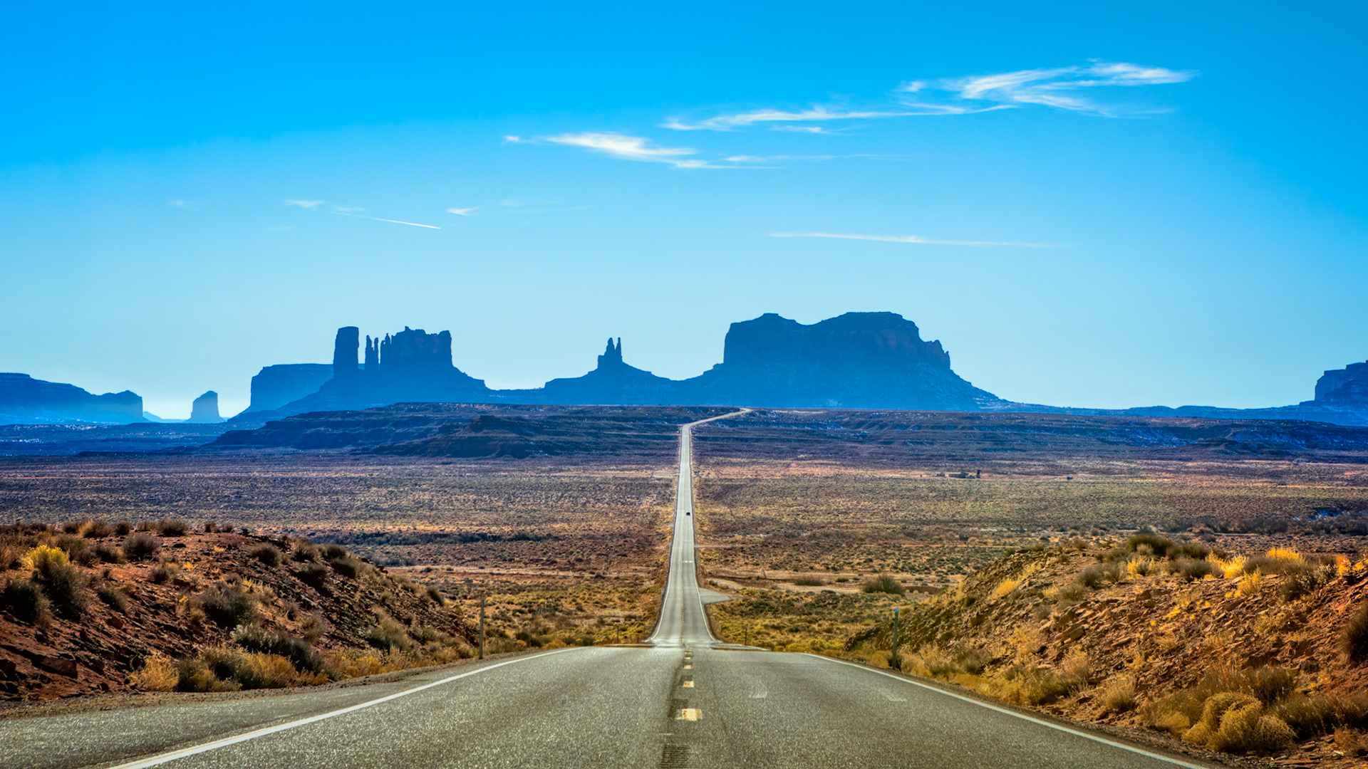 THE LONG ROAD WEST  |  There are certain roads that become destinations in their own right.This is one of them.As I crested the rise and saw the highway stretching endlessly toward Monument Valley, I immediately understood why this view has become one of the most photographed roads in America. The asphalt ribbon seemed to pull the eye straight into the heart of the desert, leading toward a horizon filled with legendary sandstone monuments.Every traveler who drives this road experiences the same anticipation.With each passing mile, the buttes grow larger. Their silhouettes slowly transform from distant shapes into towering formations that dominate the landscape. The journey itself becomes part of the experience.What makes this scene so compelling is its simplicity. A road. A horizon. A destination.Yet together they create something powerful.The road invites us forward. The desert reminds us of the vastness of the American Southwest. The monuments on the horizon stand as silent promises of adventure waiting just ahead.I stopped for only a few minutes to make this photograph, but I suspect nearly everyone who travels this route feels the same urge. Some scenes are simply impossible to drive past.They call you to stop, look, and appreciate the journey.Not just the destination.