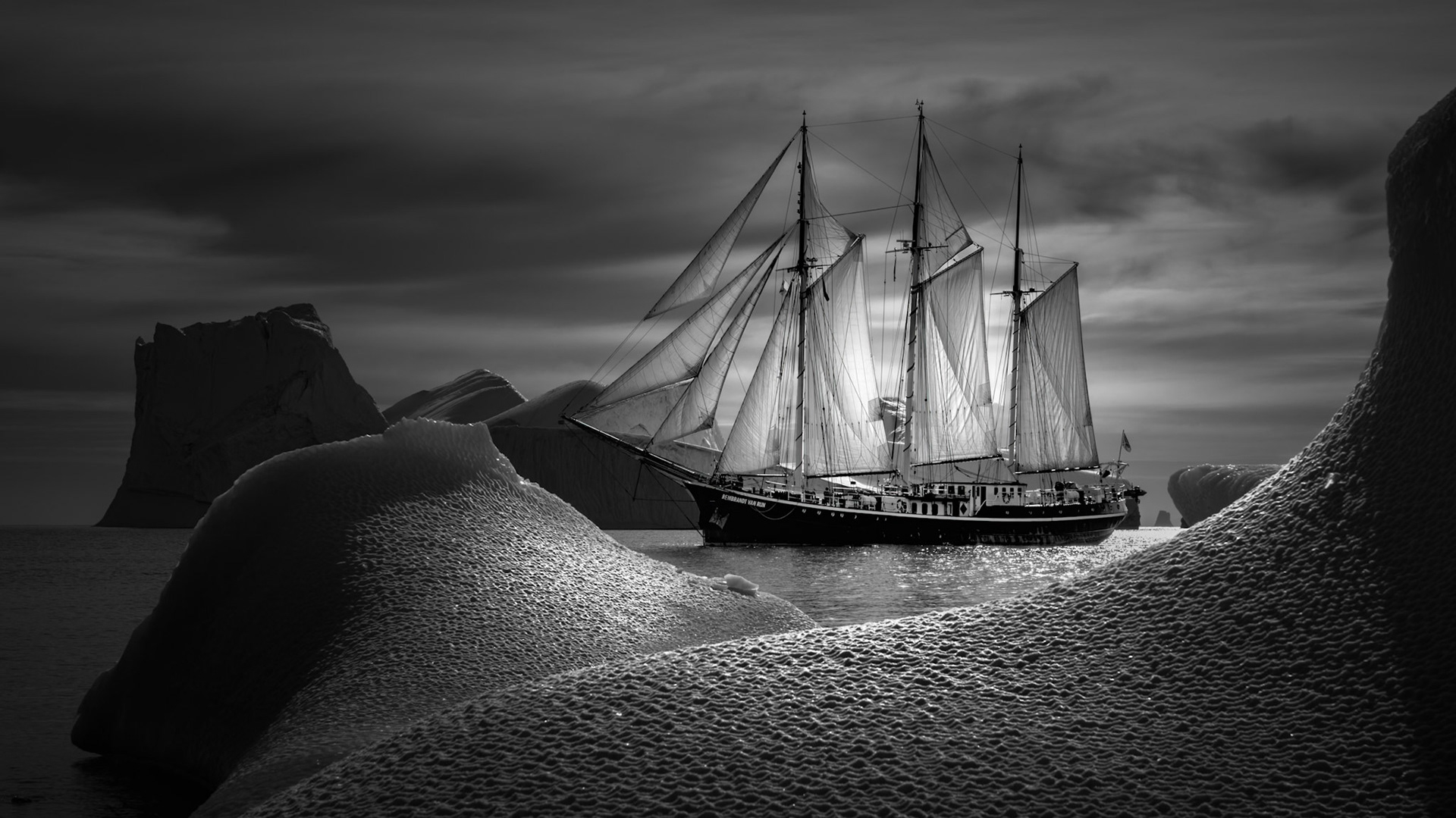 GHOST OF SCORESBY SOUND | The Rembrandt van Rijn drifts through Scoresby Sound like a ghost from another age, her tall masts and luminous sails rising among the sculpted ice with a quiet, almost dreamlike grace. Built in 1924 in Leiderdorp, the Netherlands, she began life as a herring schooner before becoming the elegant expedition vessel that now seems perfectly at home in Greenland’s haunting polar light.
