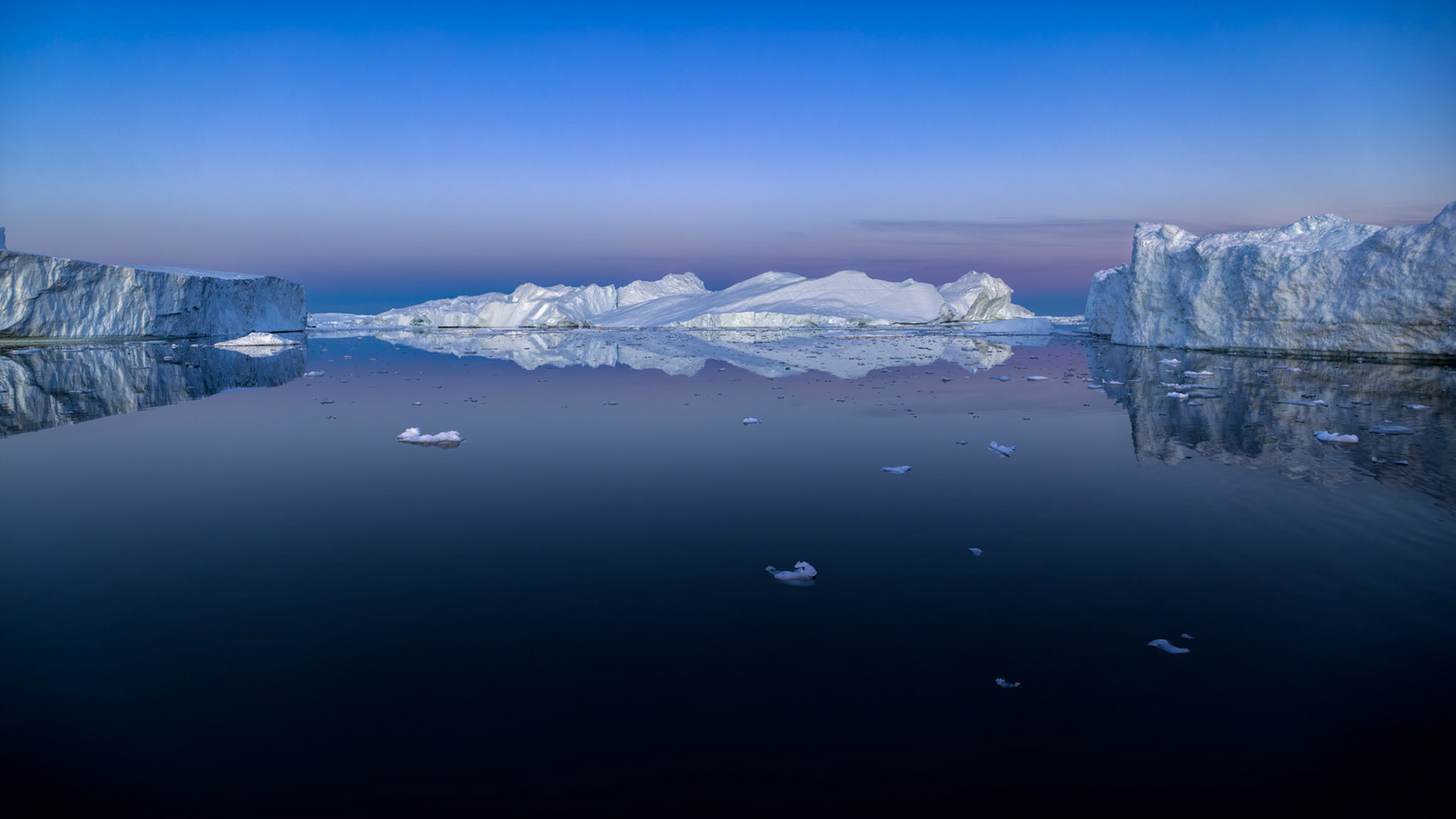 INFINITE CALM  |  At 3:30 am in  Greenland, the sea becomes a mirror and the world grows silent. Icebergs drift across water so calm that the boundary between reality and reflection nearly disappears, while the soft pastel glow of the Arctic sky lingers long after sunset.What struck me most about this scene was the overwhelming sense of stillness. There were no crashing waves, no wind, no movement beyond the slow passage of ancient ice. Standing there felt less like observing a landscape and more like witnessing a moment suspended in time.In a place defined by extremes, it is often the quiet moments that leave the deepest impression. This image is a reminder that nature's greatest power is not always found in drama, but in serenity.