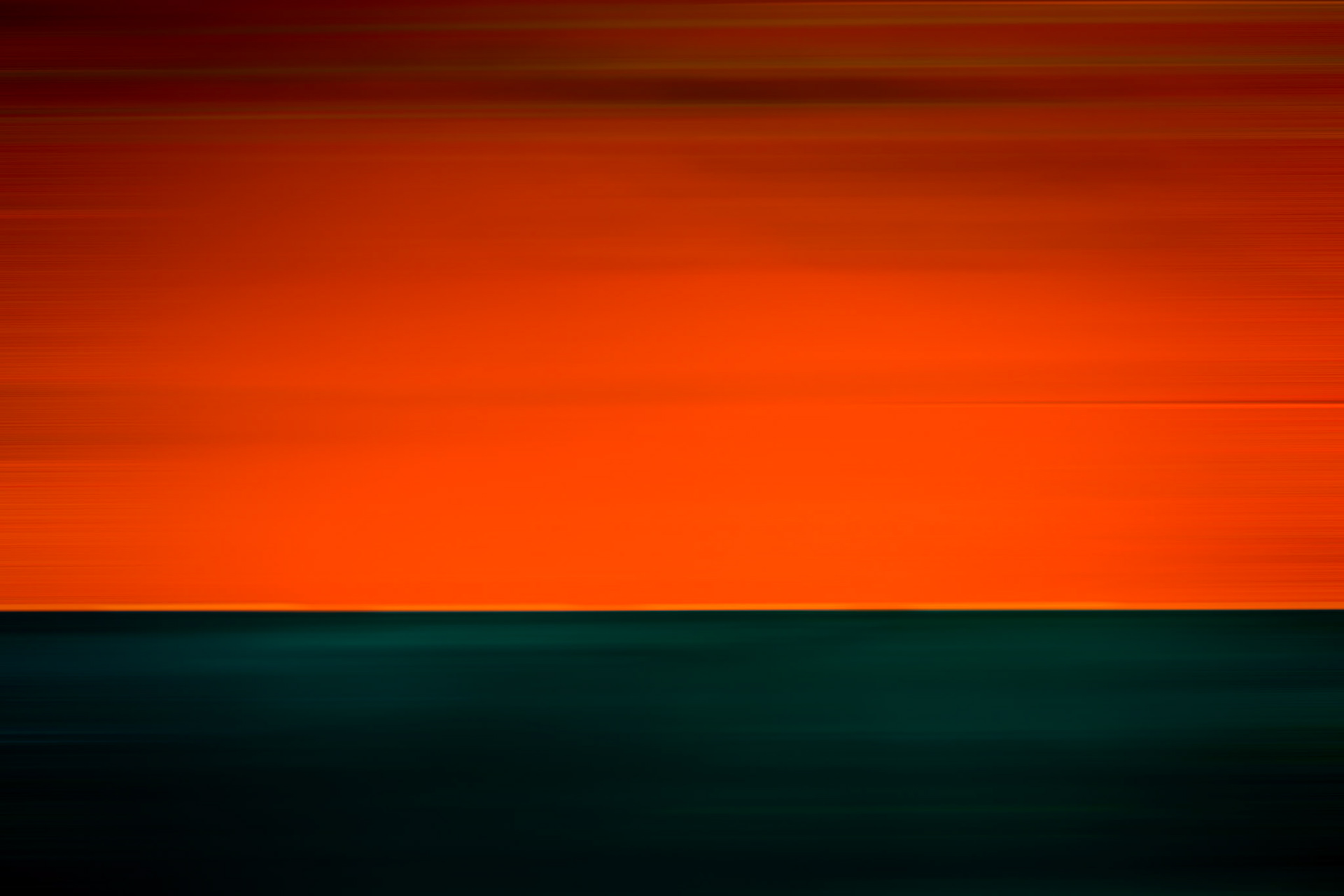 MOLTEN HORIZON  |  Most people see a tanker. I see a survivor.These massive vessels spend decades crossing oceans, carrying the cargo that quietly keeps the world moving. They endure storms, salt, endless sunrises and sunsets, and the relentless wear of time. Like weathered barns standing alone on the prairie, they become monuments to hard work, endurance, and purpose.What drew me to this ship was not its size, but its surface. Layers of paint, rust, scars, and repairs told a story written over many years at sea. Every mark hinted at a journey, every texture a chapter. Standing close enough that the vessel became abstract, I was no longer photographing a ship. I was photographing history.The rich orange and deep blue tones create a simple composition, reducing the subject to color, line, and atmosphere. The horizon divides the frame like a distant ocean meeting an endless sky, while the blurred textures suggest motion, memory, and the passage of time.I often refer to these vessels as "Barns of the Sea." Like old farm buildings, they may not be elegant in the traditional sense, but they possess a character earned through years of service. Their beauty comes not from perfection, but from experience.