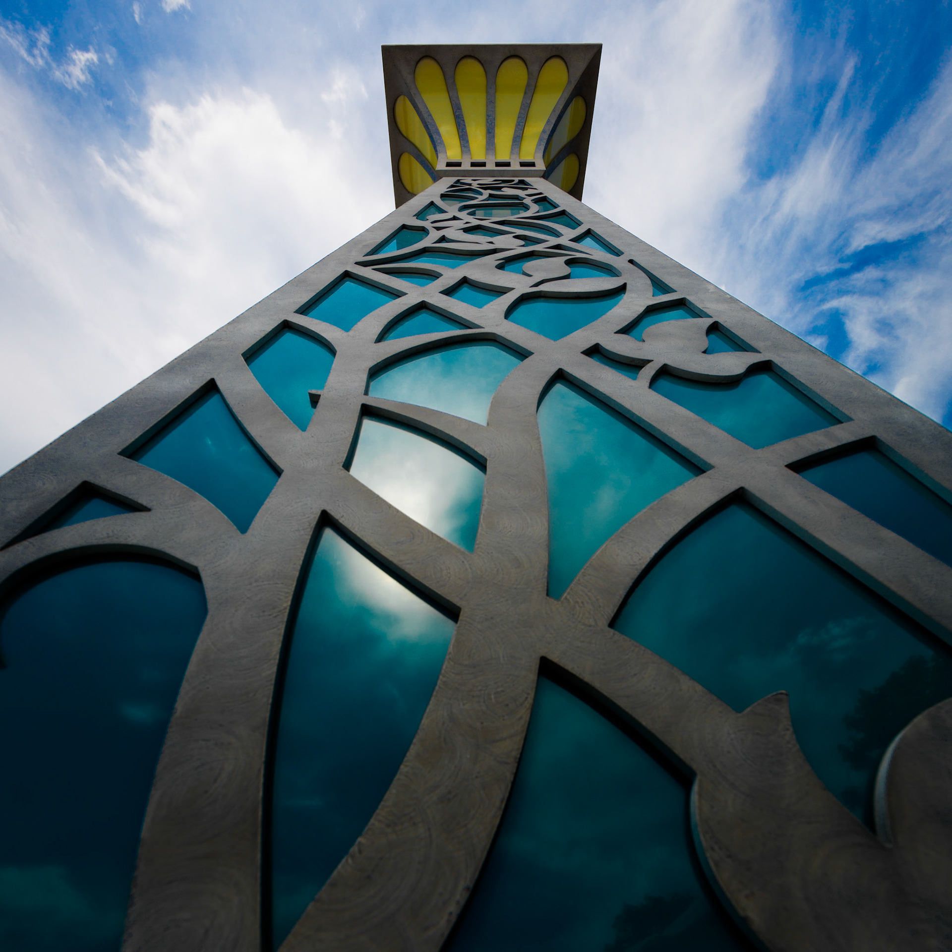 SKYWARD TOWER  |  The soaring lines and intricate patterns draw the eye upward, transforming a modern architectural detail into something almost spiritual. Reflections of drifting clouds mingle with geometric design, creating a visual conversation between craftsmanship, light, and the endless sky above.