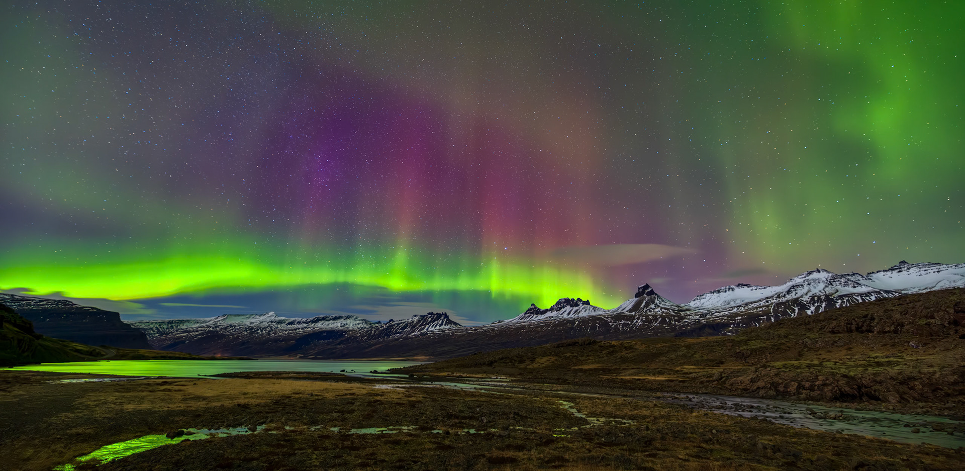 AURORA IN THE LOWLANDS  |  The northern lights are always captivating, but on rare nights they reveal an even broader palette of color. Stretching across the mountains of East Iceland, vibrant green curtains were joined by vivid shades of magenta and purple, transforming the sky into a living canvas above the rugged landscape.The display evolved constantly, shifting and dancing across the horizon while reflecting faintly in the waters below. Against the backdrop of snow capped peaks and remote wilderness, the aurora created a scene that felt almost impossible to comprehend. Moments like these are why so many travelers journey to Iceland, hoping to witness nature at its most extraordinary.