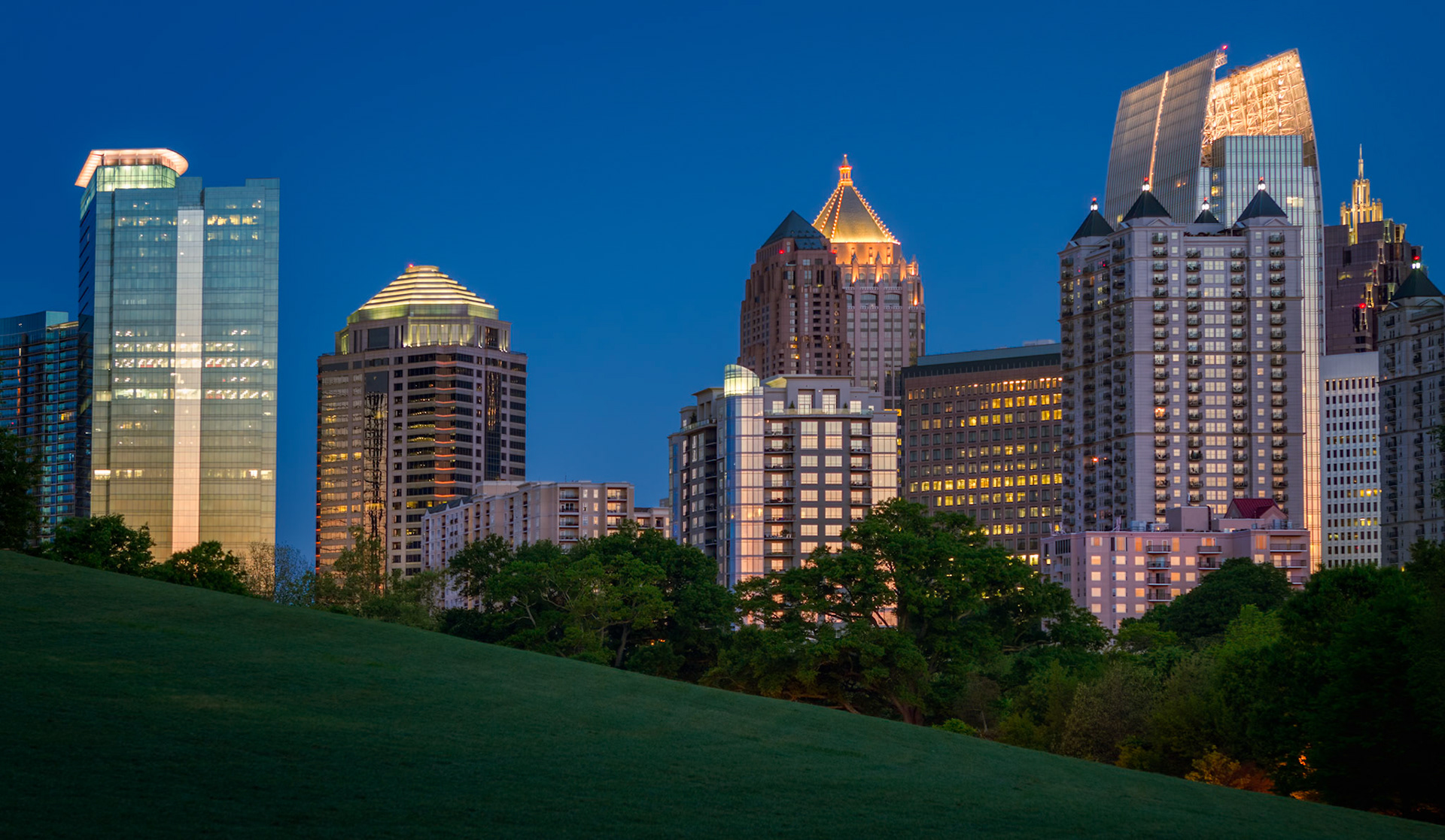 CITY IN THE DISTANCE  |  One of the things I love most about Atlanta is how much green space remains woven into the city. Standing in Piedmont Park at dusk, it was easy to forget I was in the heart of a major metropolitan area. The skyline rose above the trees, its lights beginning to glow as day quietly gave way to evening.What isn't obvious from the image is how quickly this moment passed. The balance between the deep blue sky, the illuminated buildings, and the fading light lasted only a few minutes before the scene changed completely. Those brief transitions are often my favorite part of photography because they reward patience more than planning.For me, this image reflects the unique character of Atlanta, a city where nature and architecture seem to share the same space rather than compete for it.