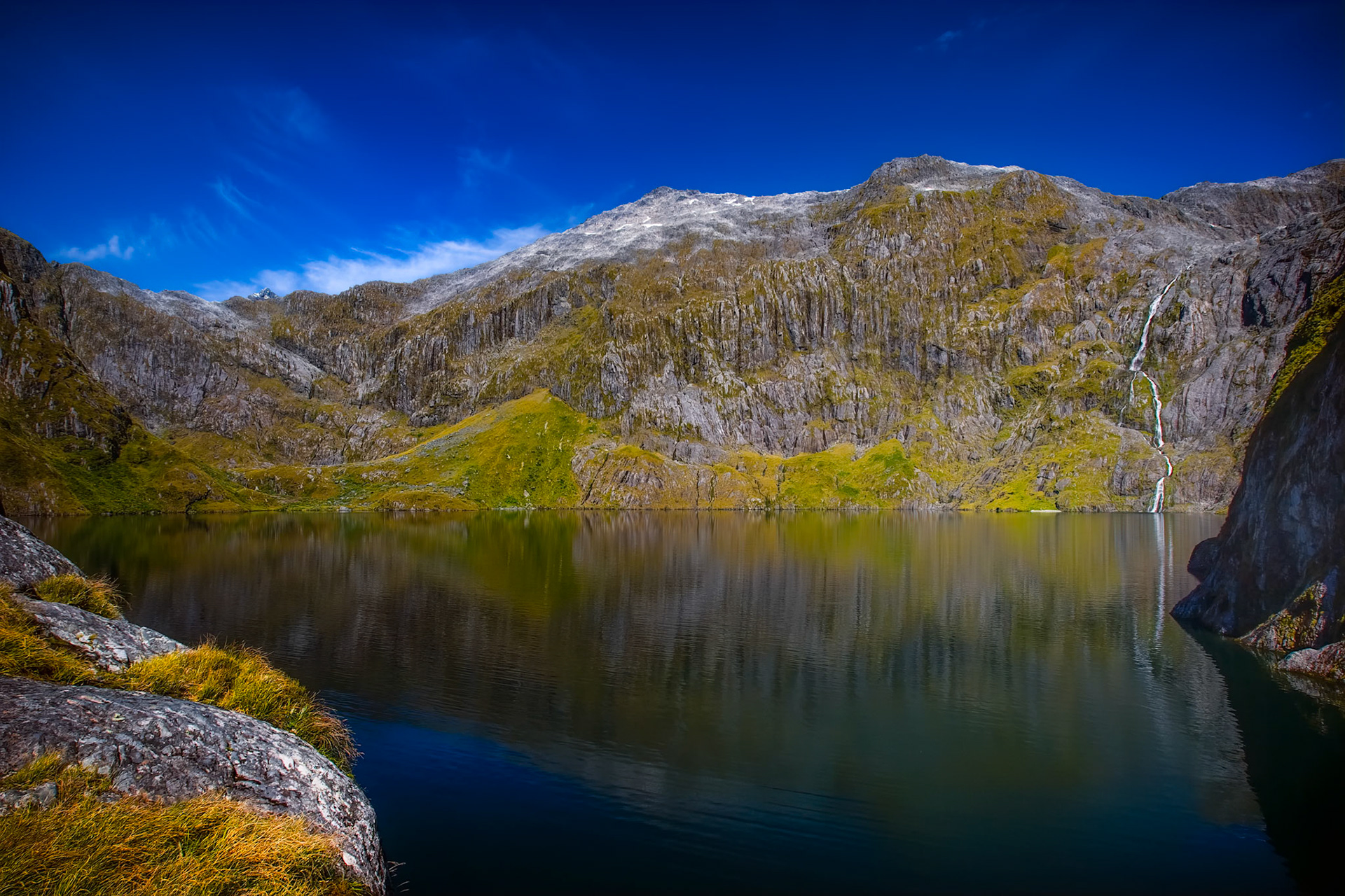 LAKE QUILL  | Reaching Lake Quill requires commitment. Perched nearly 2,000 feet above Milford Sound, this remote alpine lake sits at the headwaters of one of New Zealand's most spectacular waterfalls. The climb is demanding, but the reward is a landscape that feels untouched by time.On the day I arrived, the lake was perfectly still, transforming the surrounding mountains into a giant natural mirror. The silence was remarkable. No roads, no crowds, only the occasional sound of water cascading down distant cliffs and the wind sweeping across the high country.What makes this place so extraordinary is what lies beyond the frame. During periods of heavy rain, Lake Quill overflows to create the famous Sutherland Falls, one of the tallest waterfalls in the world. Standing beside these tranquil waters, it is hard to imagine the immense power they can unleash.
