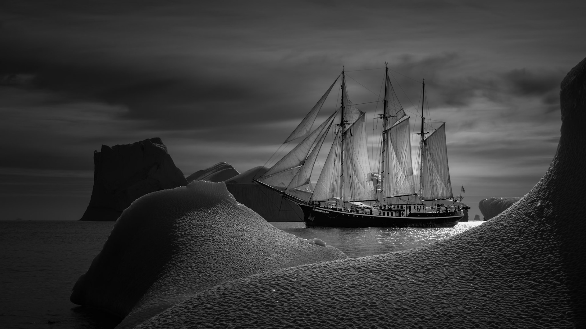 GHOST OF SCORESBY SOUND | The Rembrandt van Rijn drifts through Scoresby Sound like a ghost from another age, her tall masts and luminous sails rising among the sculpted ice with a quiet, almost dreamlike grace. Built in 1924 in Leiderdorp, the Netherlands, she began life as a herring schooner before becoming the elegant expedition vessel that now seems perfectly at home in Greenland’s haunting polar light.