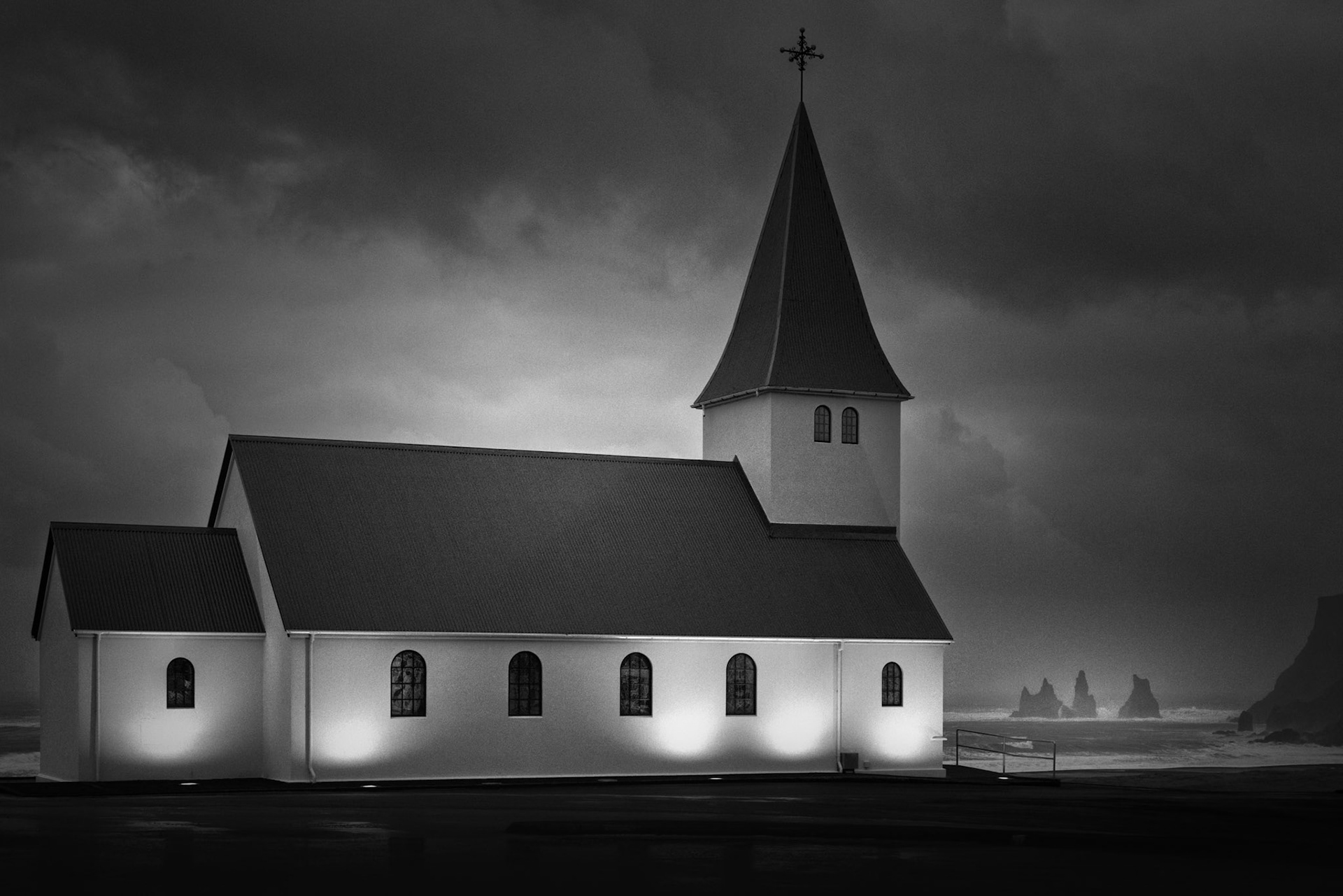 WEATHERING THE STORM  |  Perched above Iceland's rugged south coast, Reyniskirkja has watched over the village of Vík for nearly a century. On this day, gale force winds exceeding 60 mph swept in from the North Atlantic, shrouding the landscape in rain and sea spray as dark clouds raced overhead.The church stood unmoved against the storm. Illuminated against the gathering darkness, it became a symbol of resilience amid the raw power of Iceland's weather. Beyond its walls, the famous sea stacks of Reynisdrangar emerged through the mist, adding to a scene that felt both dramatic and timeless.