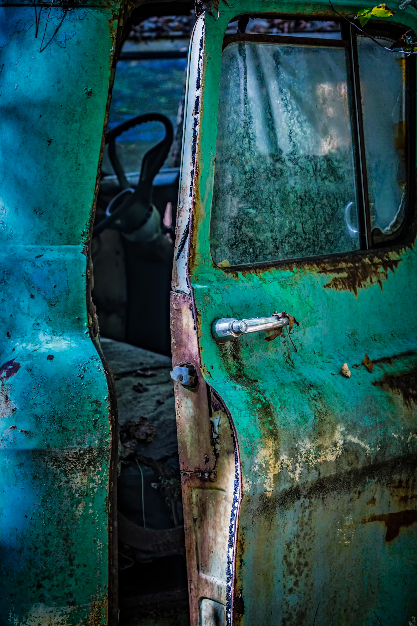 OPEN DOOR SILENCE  |  The door hangs slightly ajar, revealing just enough of the cab to spark curiosity about the journeys once taken and the people who sat behind the wheel. Decades of weather, rust, and neglect have softened the truck's hard edges, transforming it from a machine into a keeper of forgotten stories.What drew me to this scene was the invitation. The open door feels less like abandonment and more like a welcome, offering a glimpse into a past that can never be fully known yet still lingers in every worn surface and fading layer of paint.