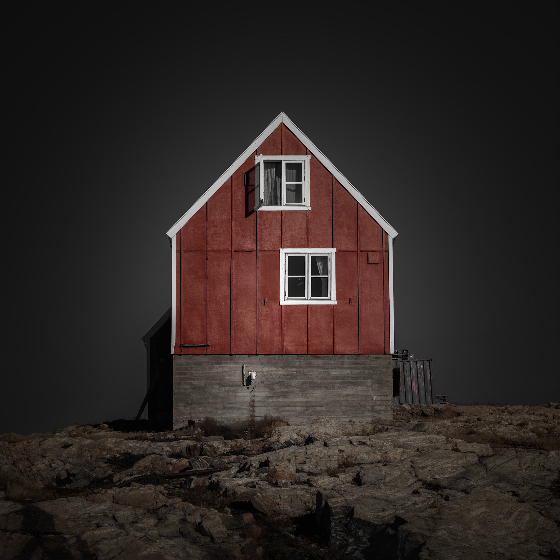 STANDING ALONE  |  Selective color.  Perched on the rocky coast of Ittoqqortoormitt in Greenland's Scoresby Sound, a solitary house stands against the vast Arctic sky.