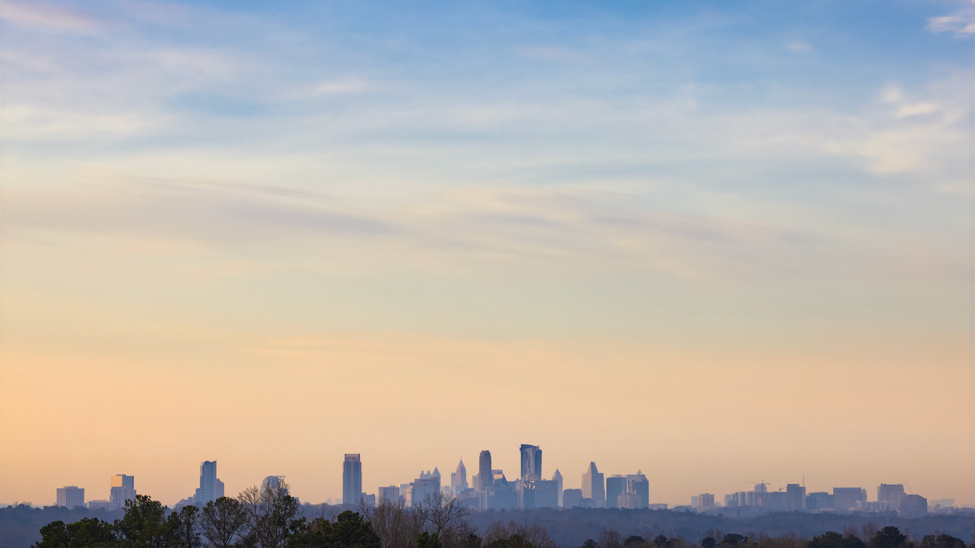 BETWEEN LIGHT  |  Atlanta's skyline rises on the horizon, viewed from Sandy Springs as layers of trees and soft morning haze create a sense of depth and scale. This peaceful perspective highlights the unique blend of urban energy and natural beauty that defines the city.