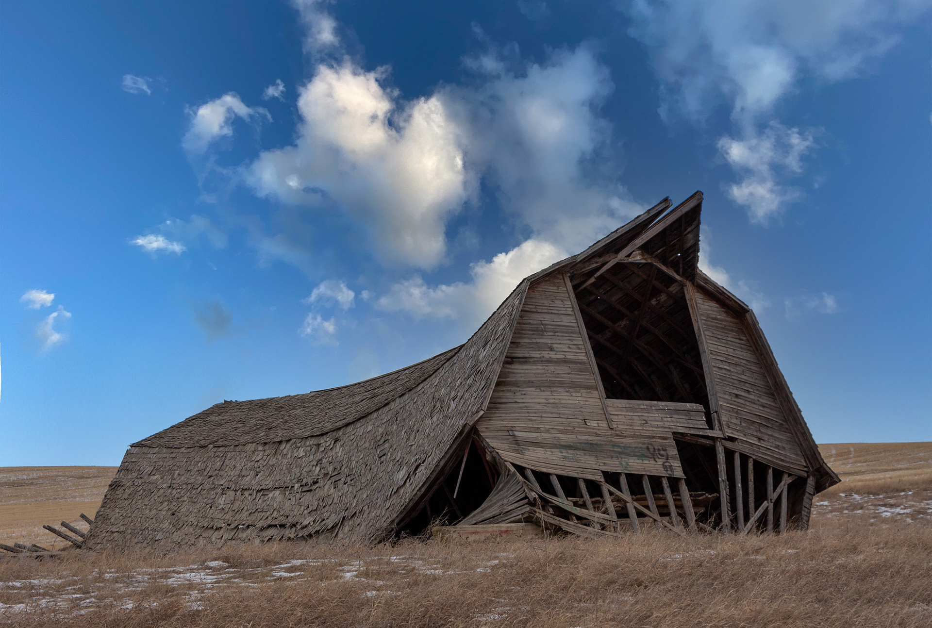 Barn with a fallen down roof, peak of roof is pointing skyward