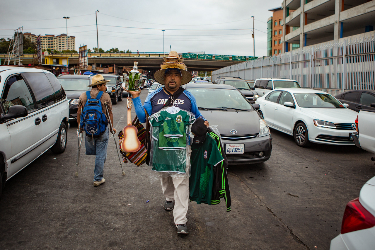 A souvenir vendor passes by a disabled man begging for money. The borderline is a crucial source of income for many Tijuana residents, whether they are selling merchandise, performing for tips or asking for donations.