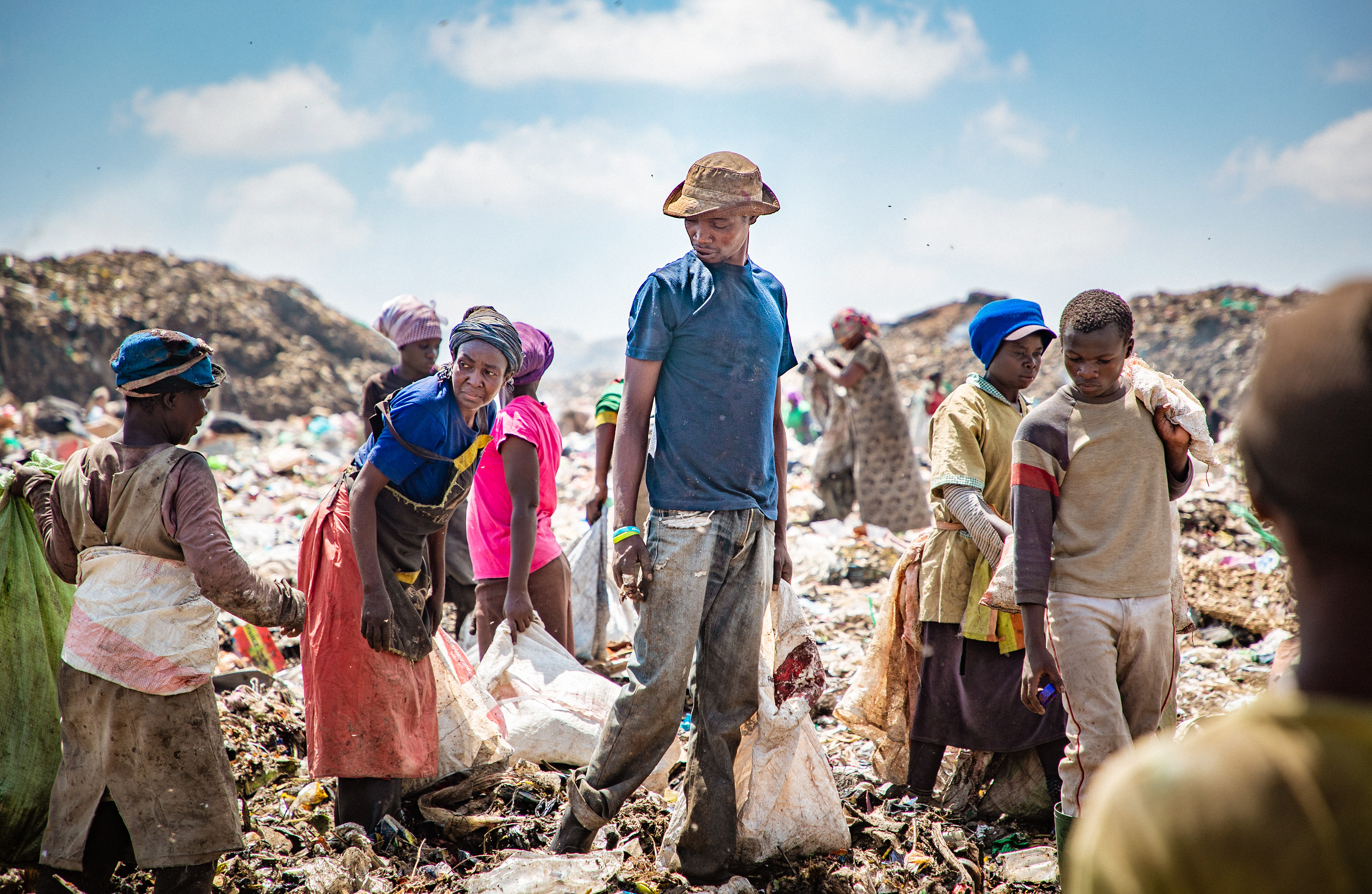 A group trails behind a bulldozer to see what it unearths. Constant fires at Dandora create a constant haze of smoke, containing mercury amongst other emissions, which will have serious negative health effects for dump workers in the long run.