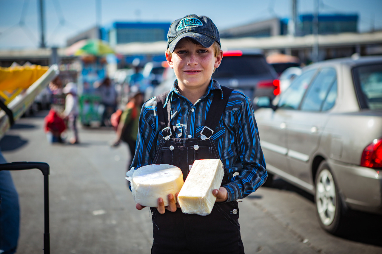 A Mennonite boy sells artisanal cheese right before the line reaches the US side of the border. Around 100,000 Mennonites are estimated to live in Mexico, descendants of Canadian settlers that travelled south in the 1920s so they could live freely in traditional agricultural communities.
