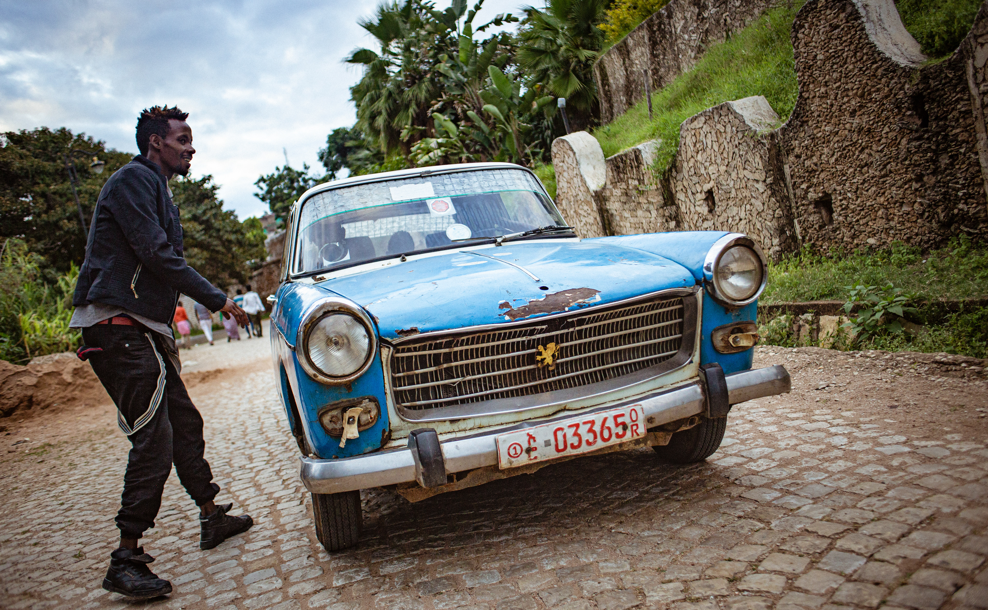 A passenger hails a Peugeot 404 cab just outside the old city walls.