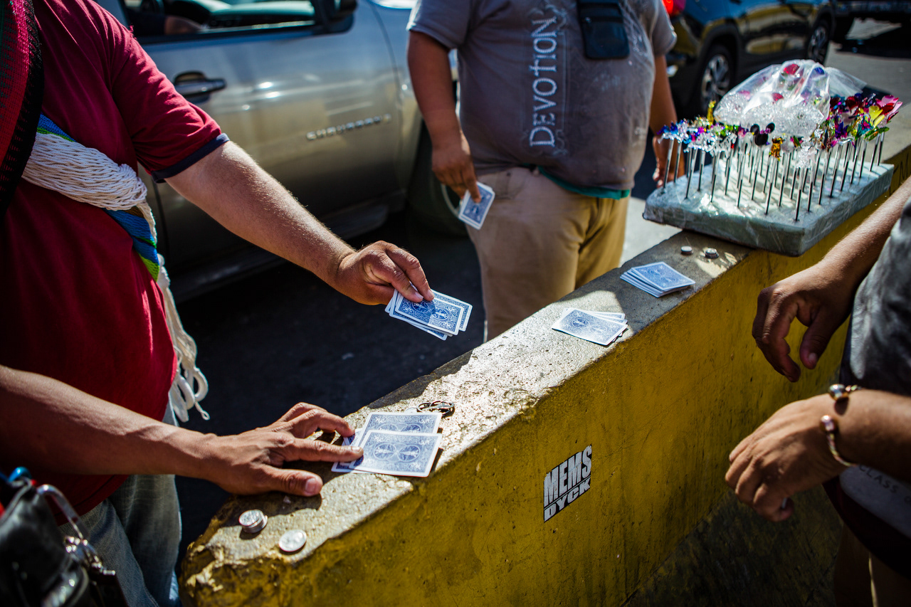 Vendors gamble in between cars while taking a break from the heat.