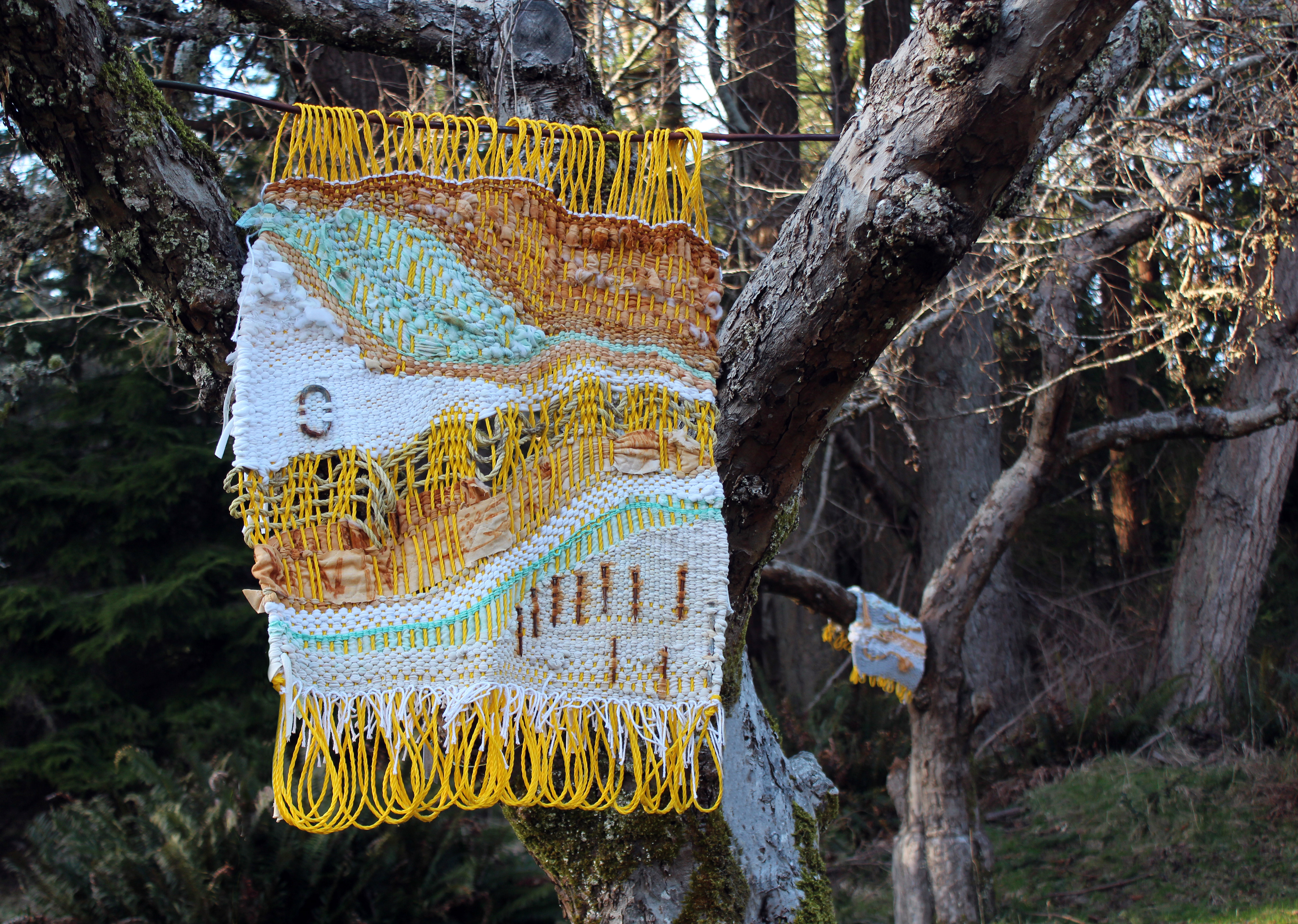 Weavings hanging in the heritage orchard. Materials: rope, metal, rust dyed recycled textiles.