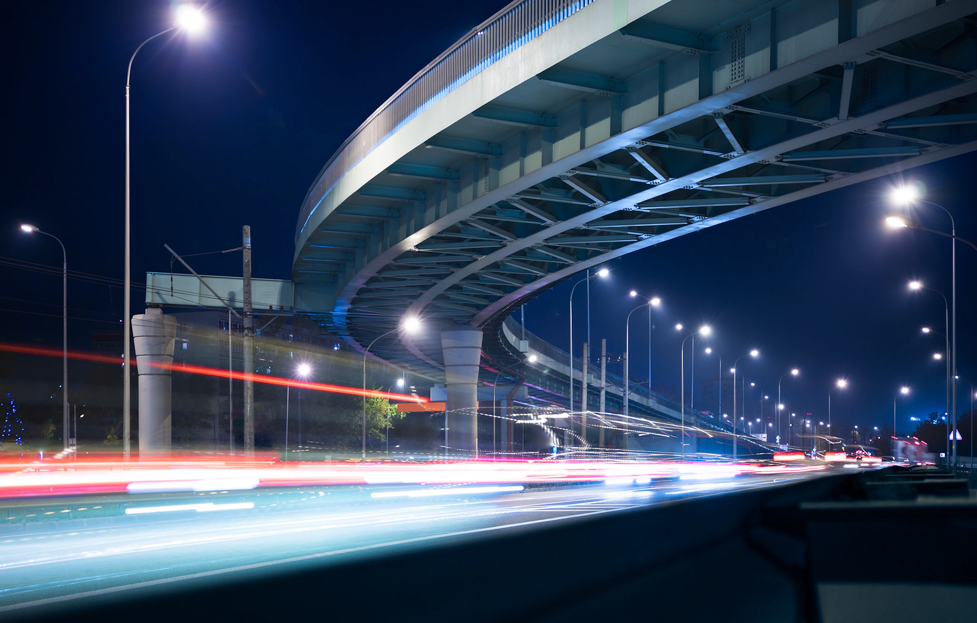 Overpass and light trails at night on the illuminated highway