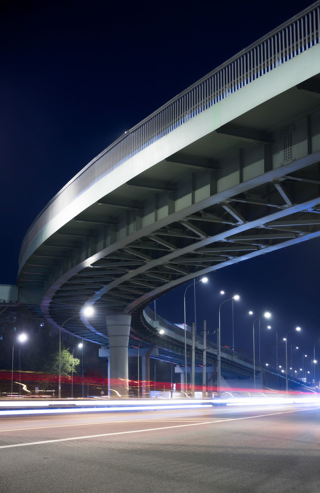 Overpass and light trails at night on the illuminated highway