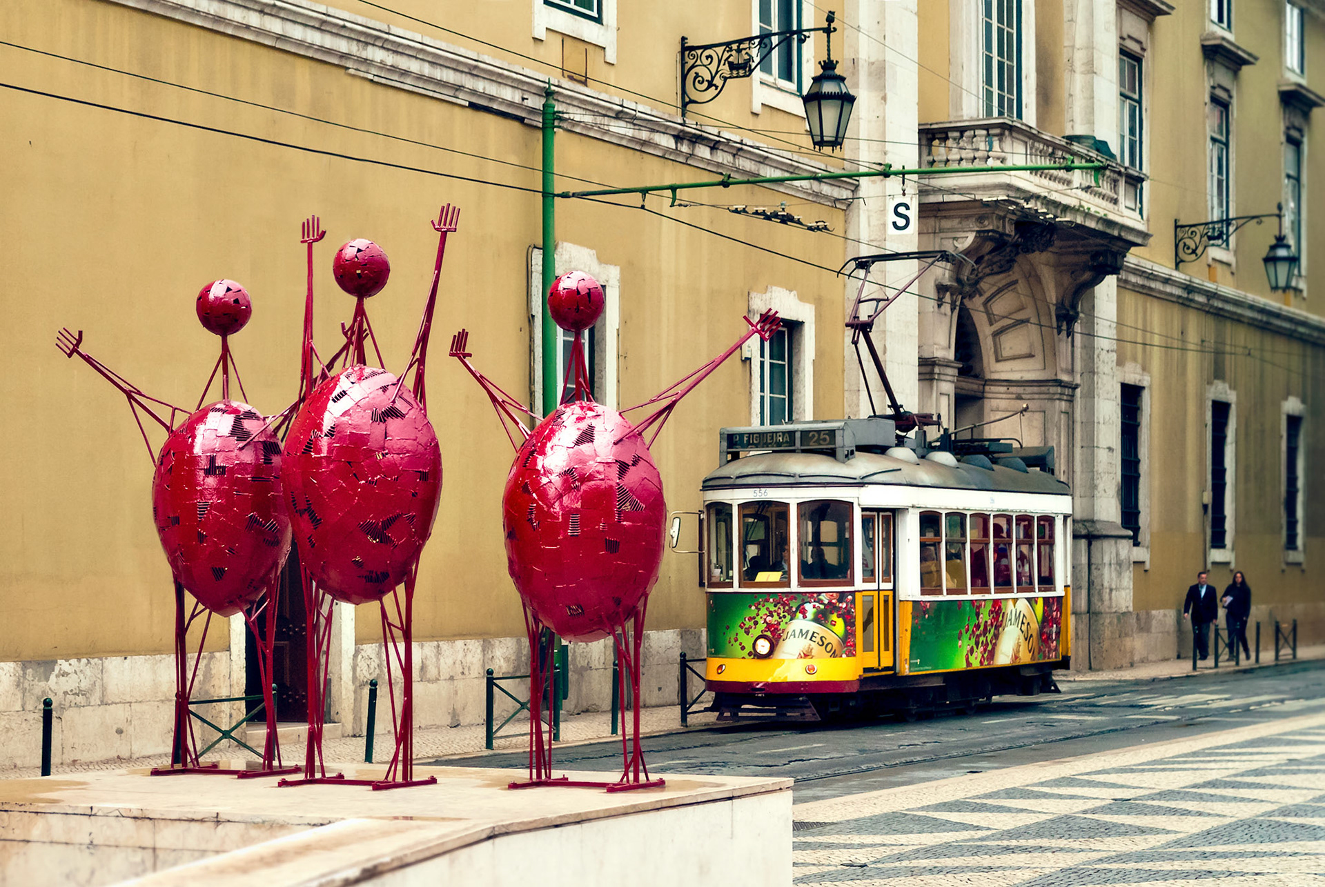 LISBON, PORTUGAL - MAY 2: Traditional yellow tram and three red statues on May 2, 2012 in Lisbon. Trams are used by everyone and also keep the traditional style of the historic center of Lisbon.