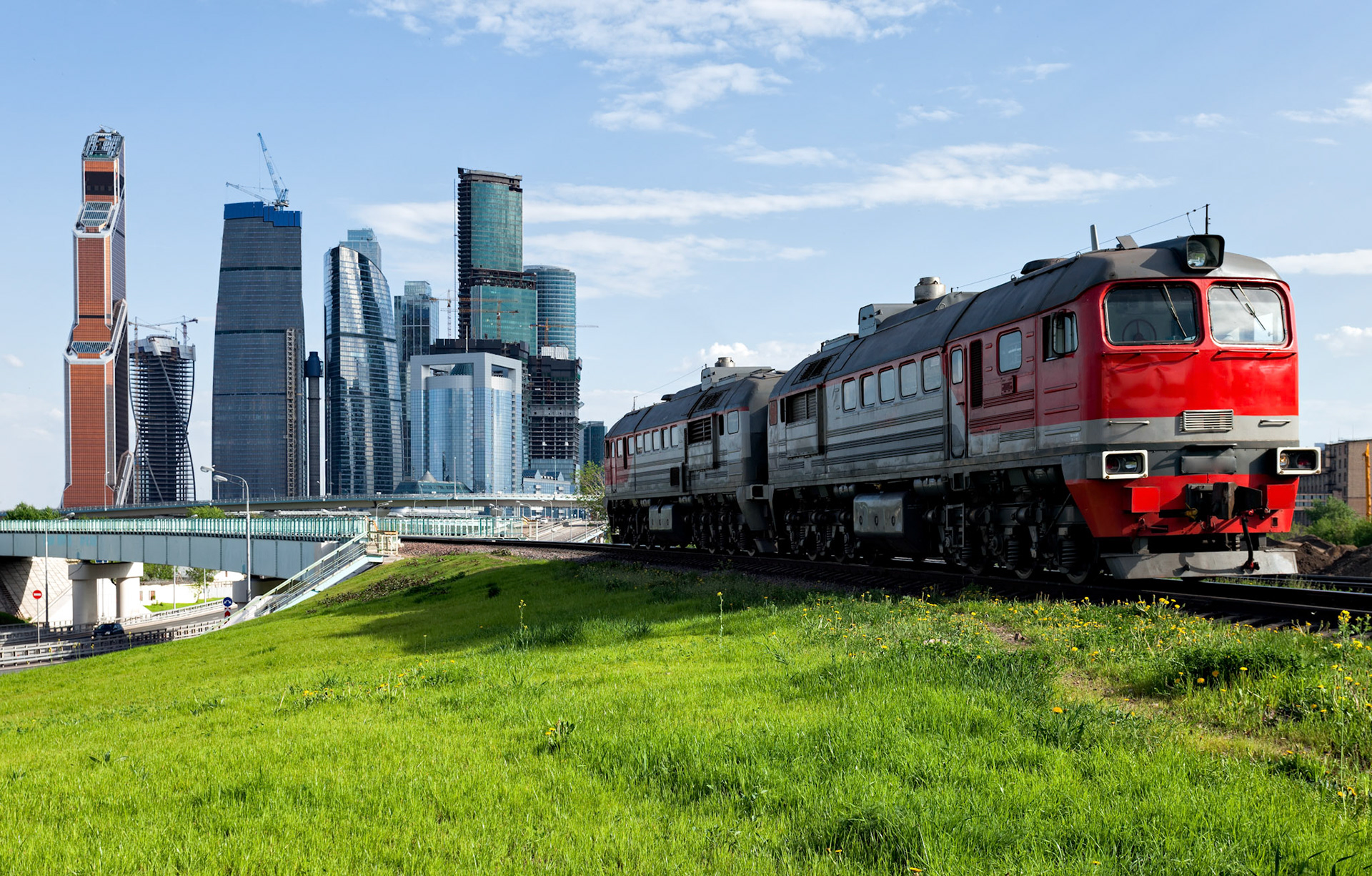 Green lawn and red train with Moscow-city on the background