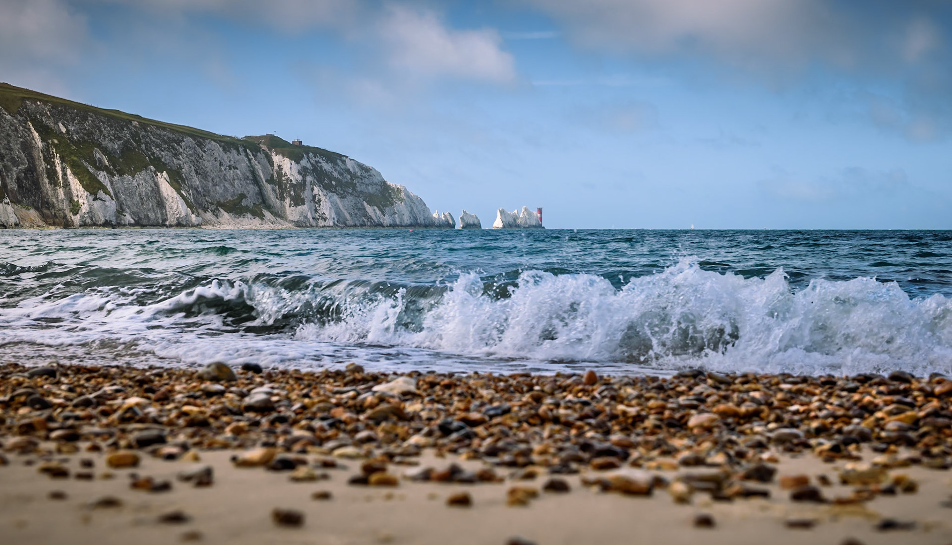 Low level view from Alum Bay beach acroos sand and shingle to the needles lighthouse
