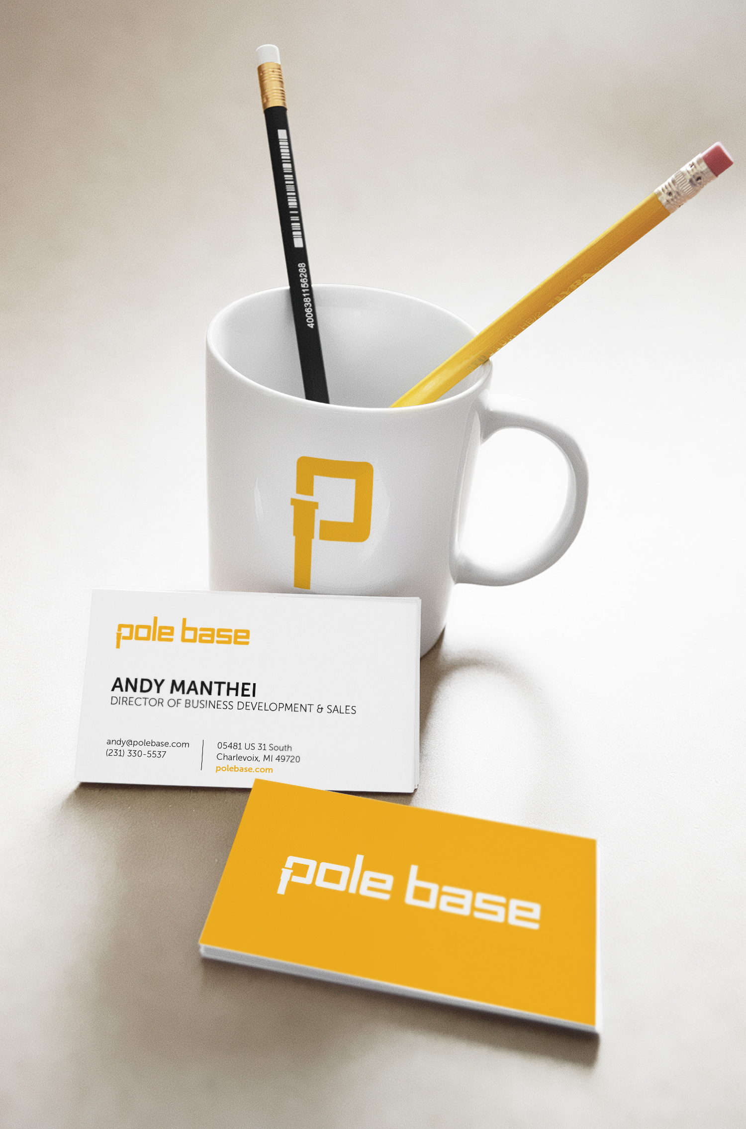 Pole Base branding showcase. A white mug with yellow symbol and a front and back of a Pole Base business card is shown.