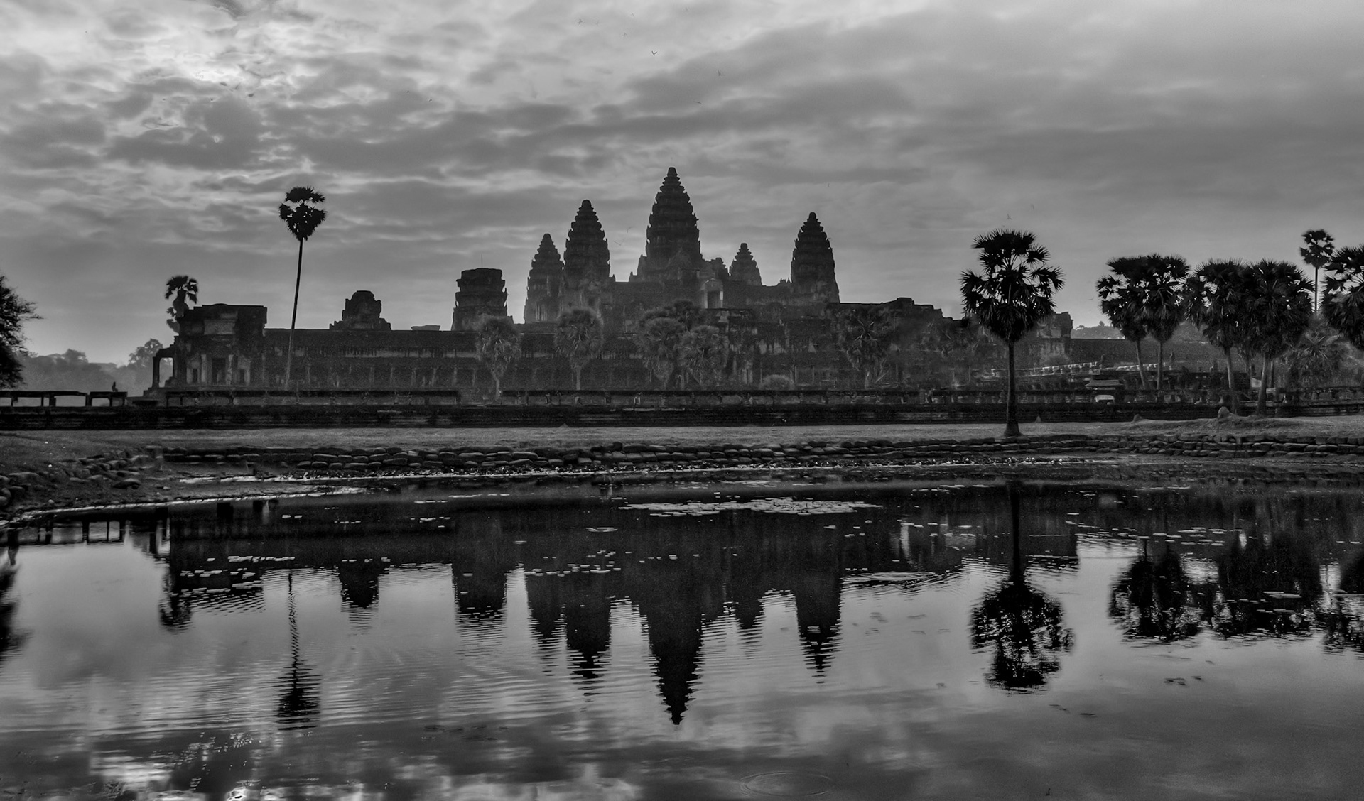 Angkor Wat is a temple complex at Angkor, Cambodia, built by King Suryavarman II in the early 12th century as his state temple and capital city. As the best-preserved temple at the site, it is the only one to have remained a significant religious centre since its foundation – first Hindu, dedicated to the god Vishnu, then Buddhist. The temple is at the top of the high classical style of Khmer architecture. It has become a symbol of Cambodia, appearing on its national flag, and it is the country's prime attraction for visitors. The modern name, Angkor Wat, means "City Temple".