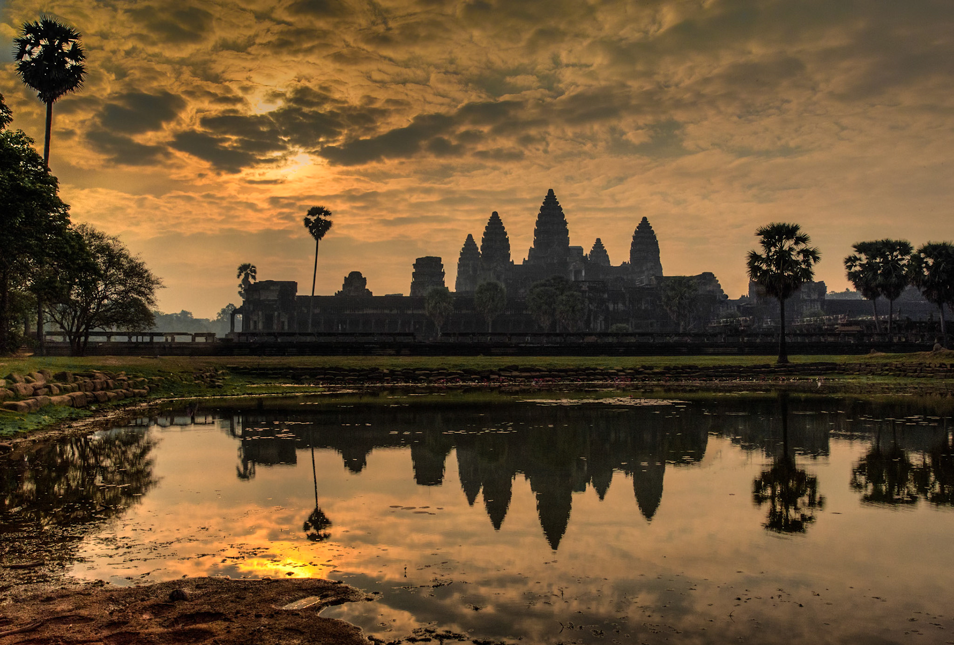 Angkor Wat is a temple complex at Angkor, Cambodia, built by King Suryavarman II in the early 12th century as his state temple and capital city. As the best-preserved temple at the site, it is the only one to have remained a significant religious centre since its foundation – first Hindu, dedicated to the god Vishnu, then Buddhist. The temple is at the top of the high classical style of Khmer architecture. It has become a symbol of Cambodia, appearing on its national flag, and it is the country's prime attraction for visitors. The modern name, Angkor Wat, means "City Temple".