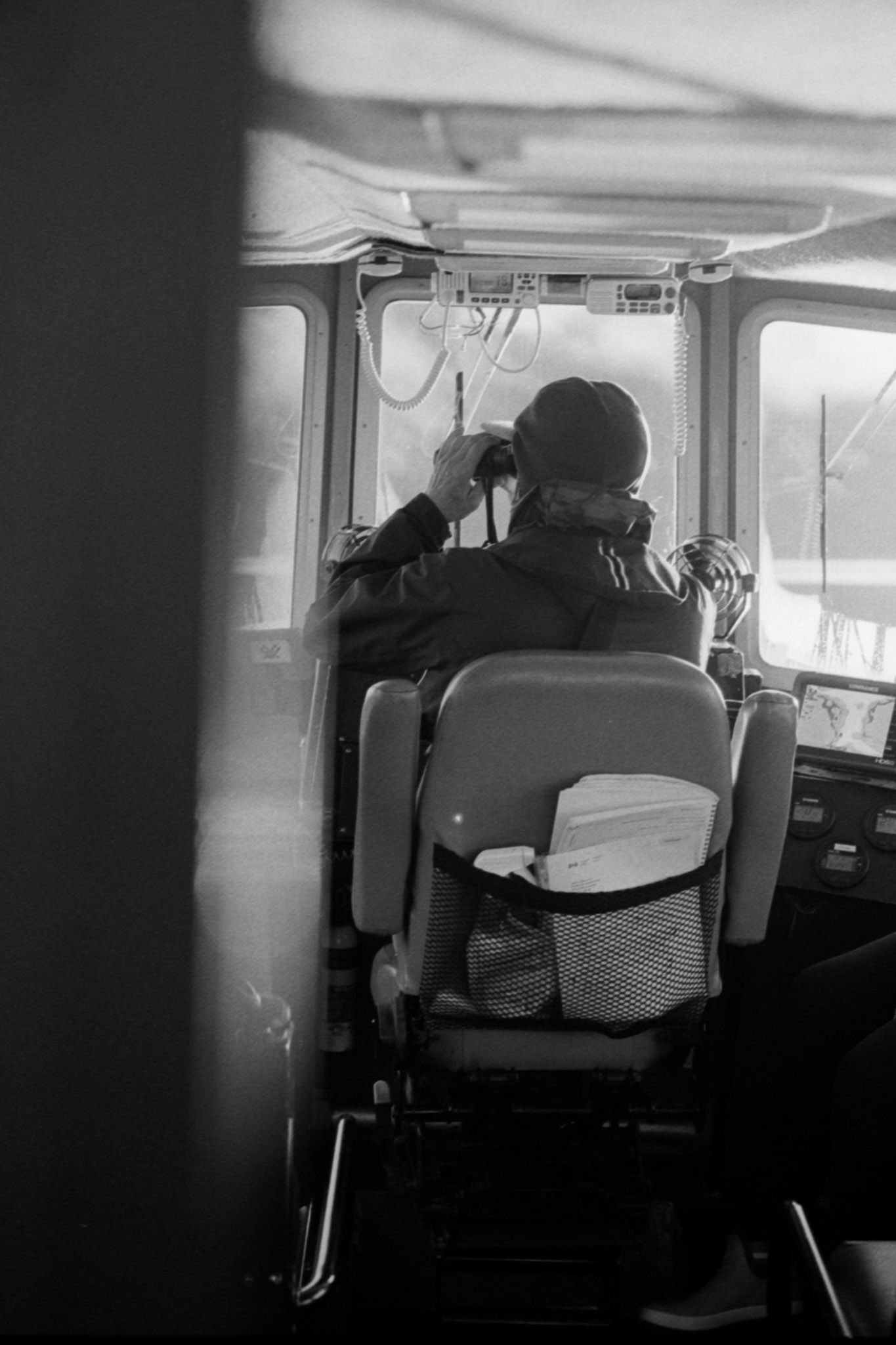 A captain scans the scene from the bridge with binoculars